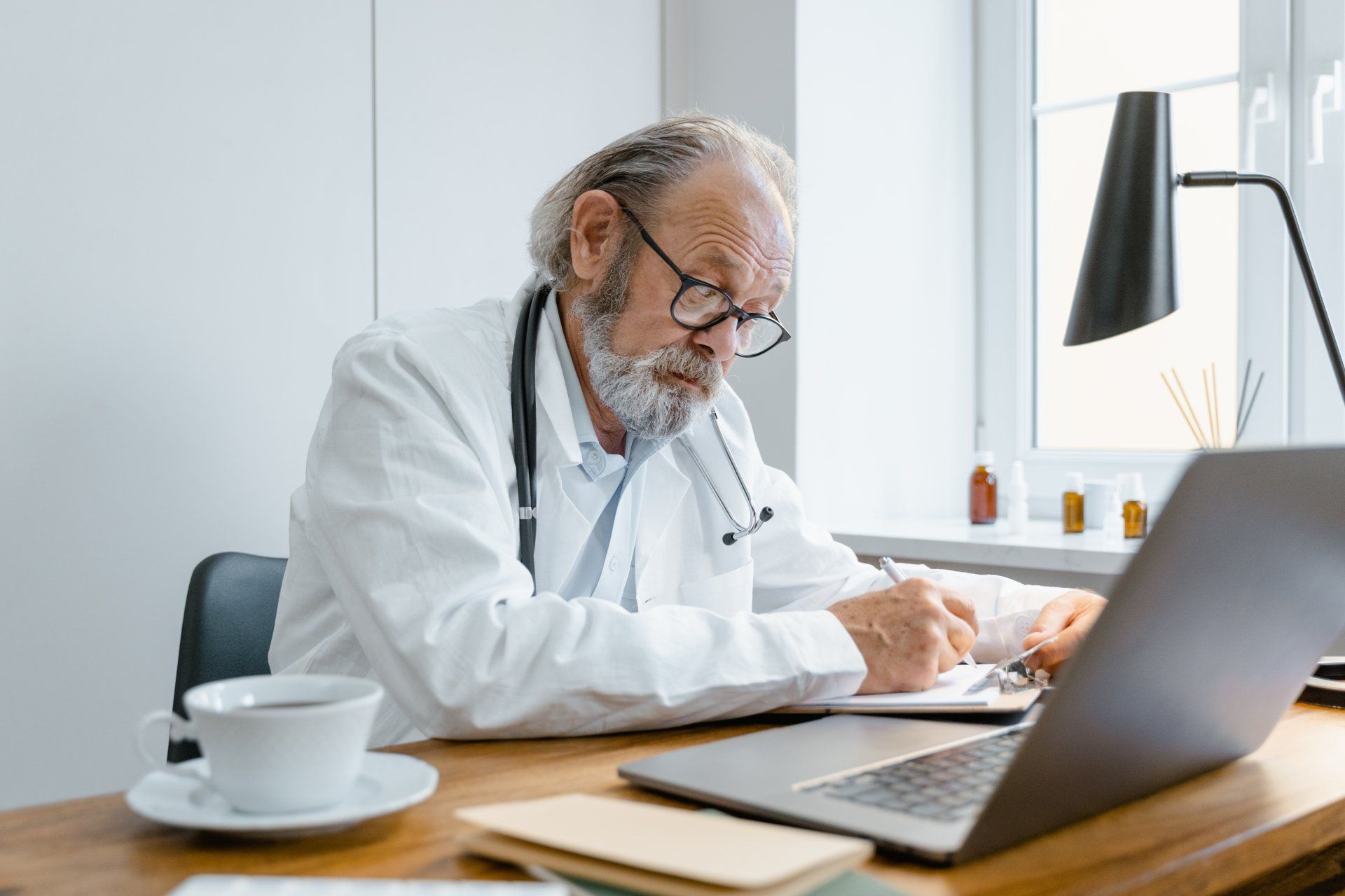 A doctor is sitting at a desk using a laptop computer.