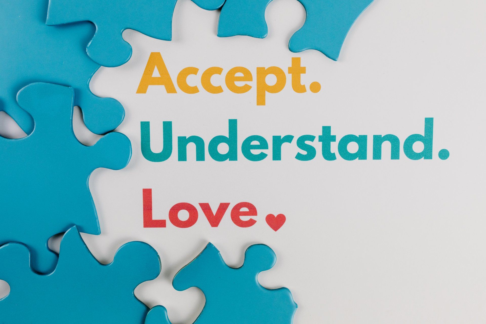 Blue puzzle pieces frame the words: Accept. Understand. Love. (with a red heart).
