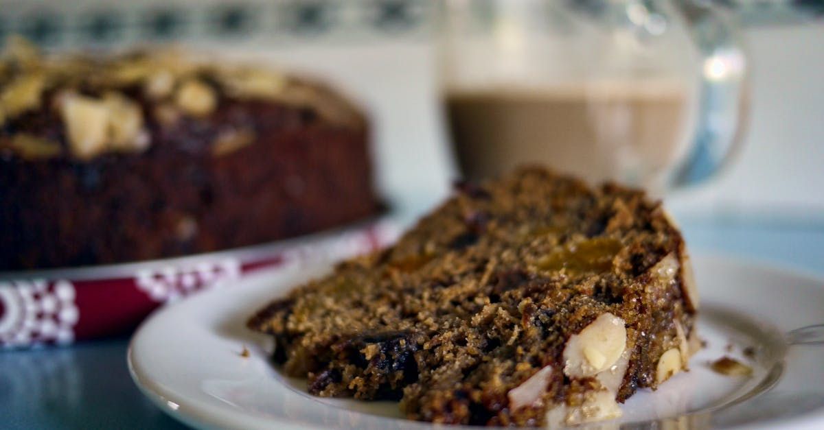 A slice of cake is on a plate next to a cup of coffee.