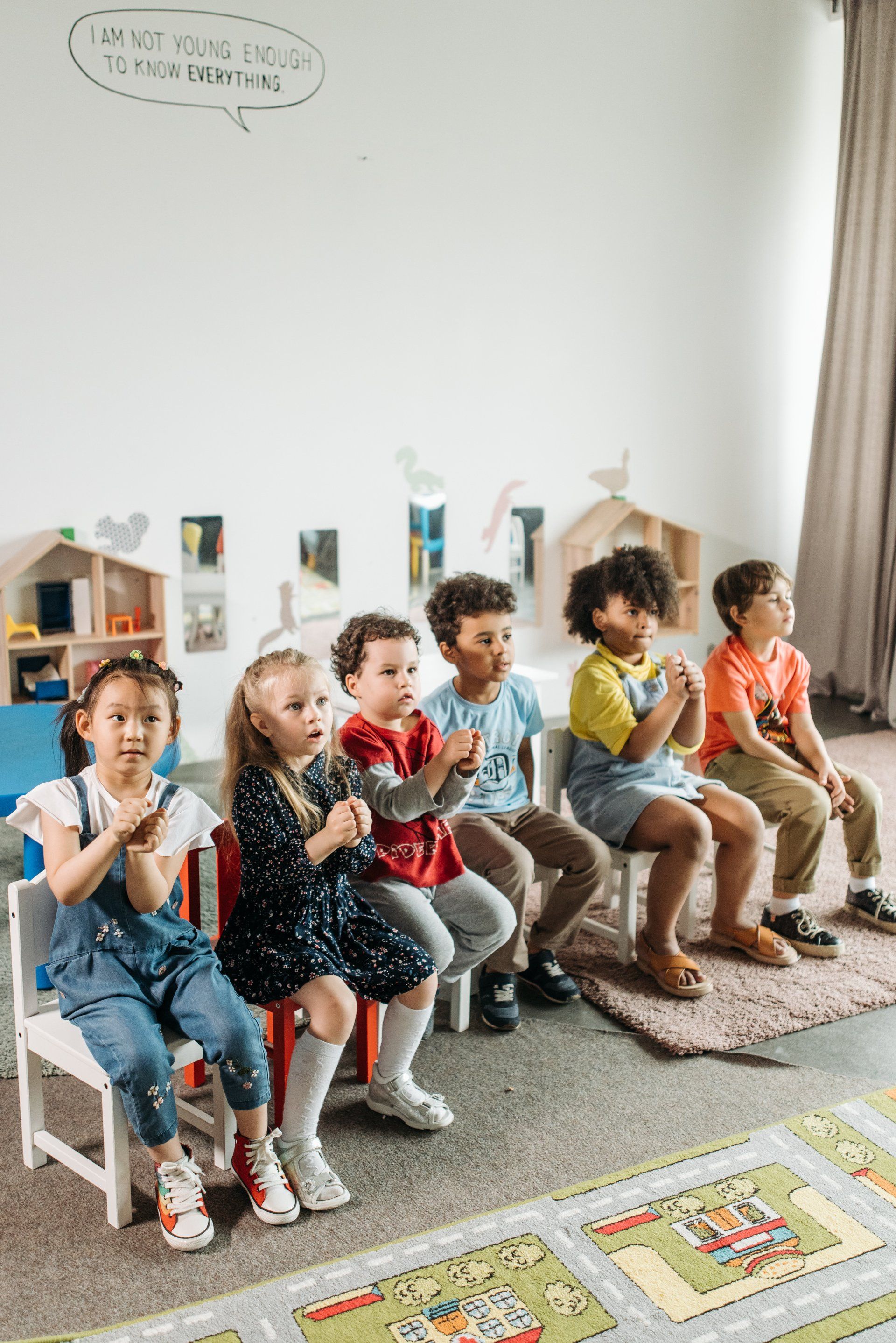 A group of children are sitting in chairs in a classroom.