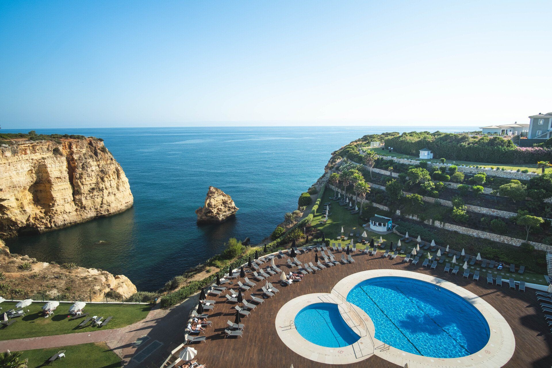 Uma vista aérea de uma piscina em um penhasco com vista para o oceano