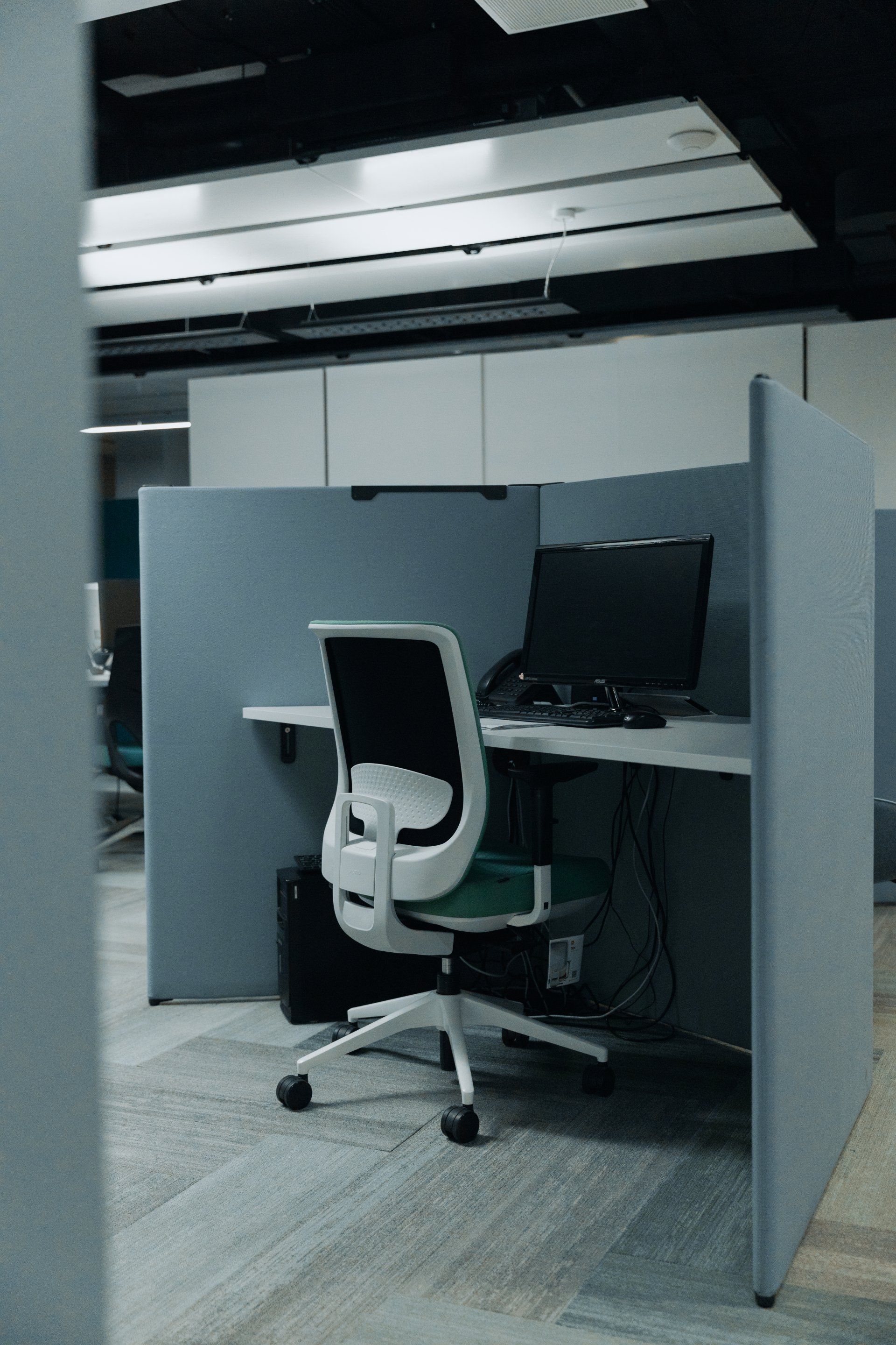 A cubicle with a chair and a computer in it.