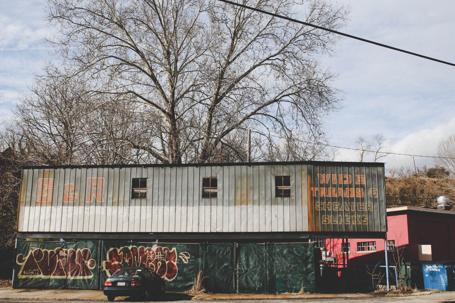 Two-story Building with a Corrugated Metal Exterior and a Green Fence | A-1 Brightside Auto LLC