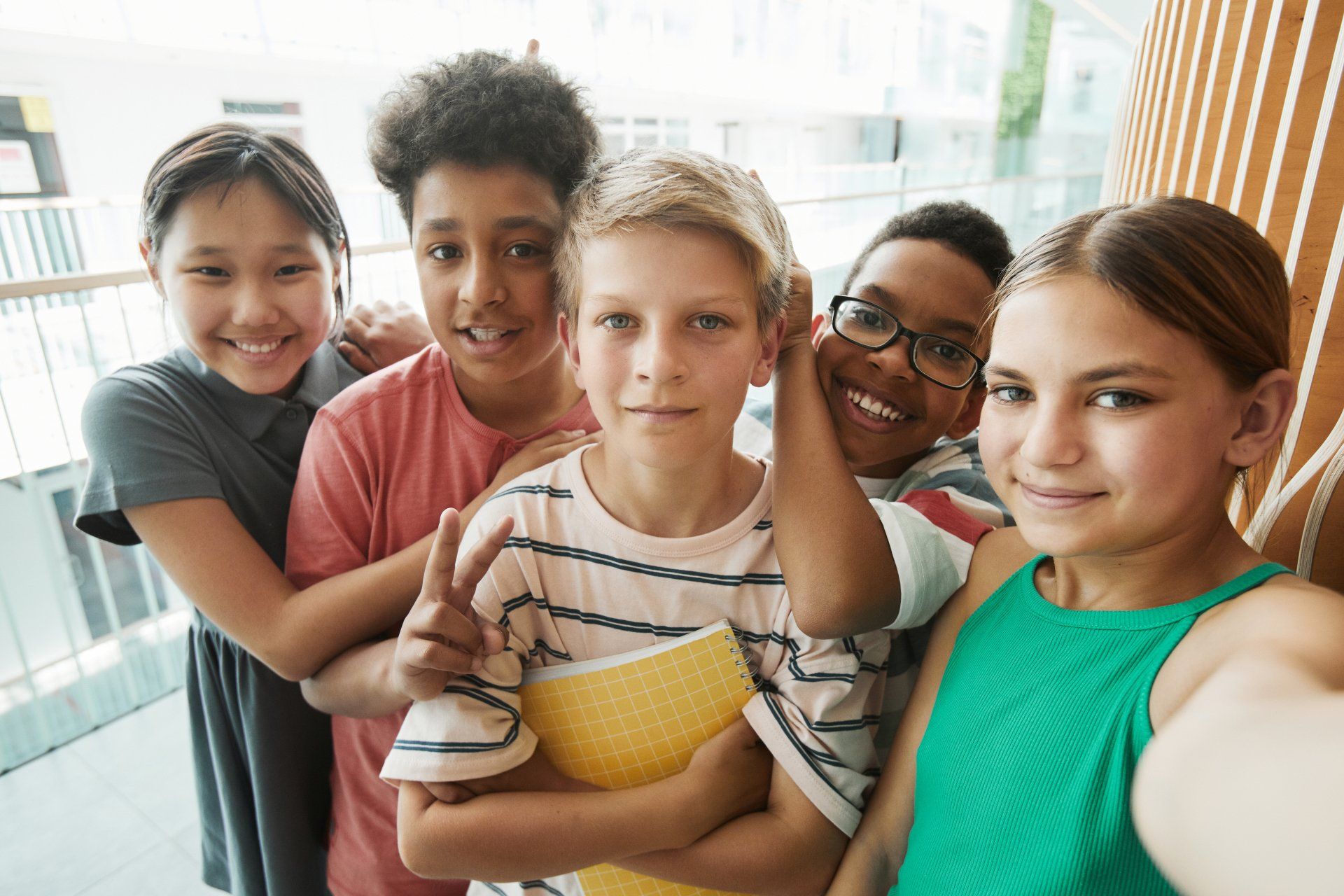 Group of five smiling children, taking a selfie.