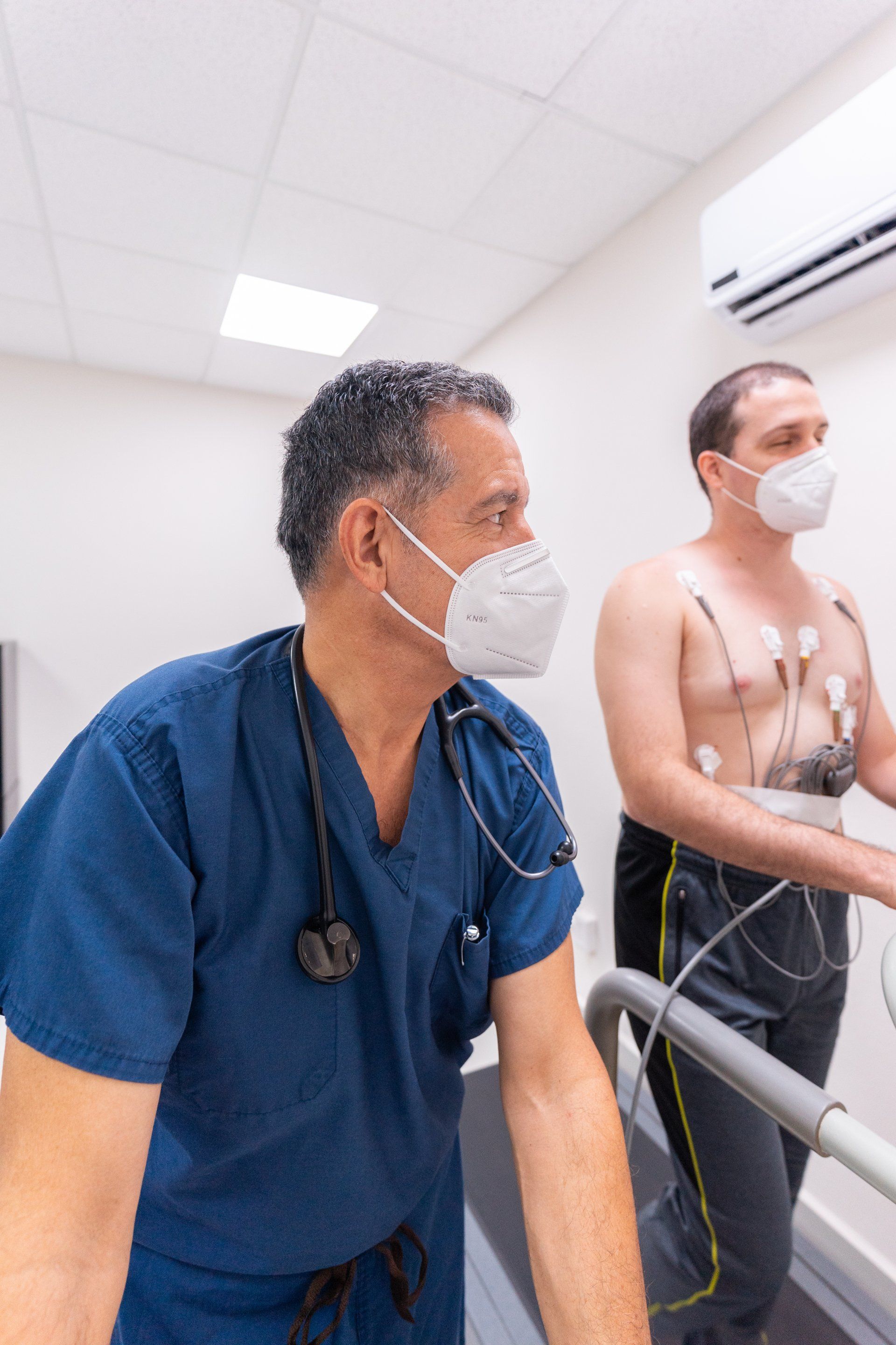 Two men wearing masks are standing next to each other on a treadmill.