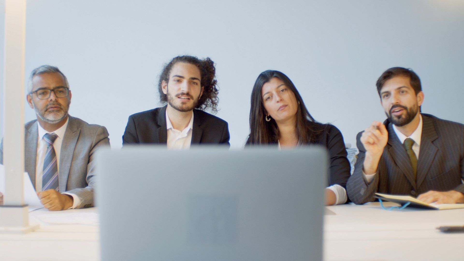 A group of business people sitting in front of a laptop computer.