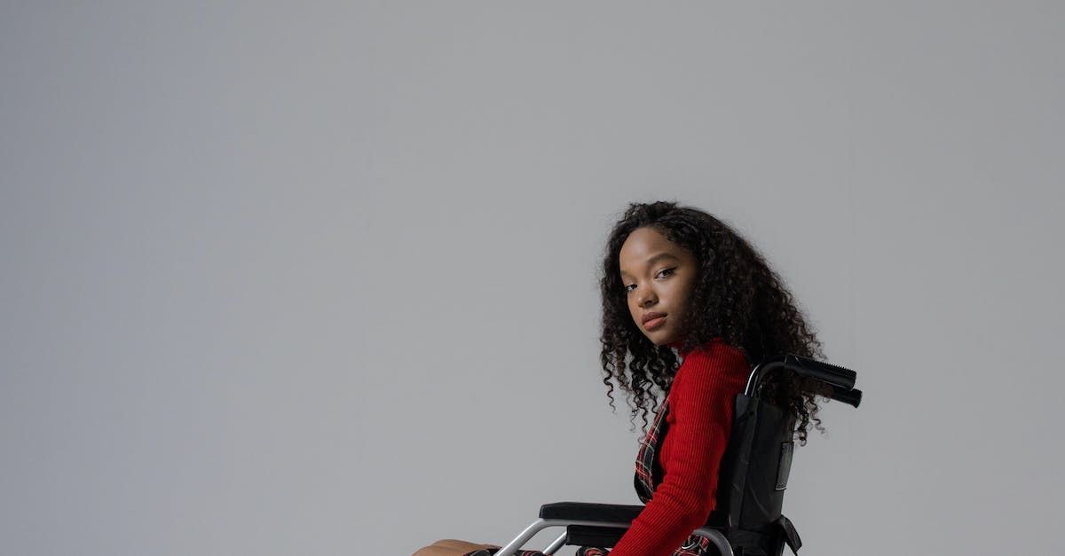 Young girl wearing red top in a wheelchair looking at camera smiling