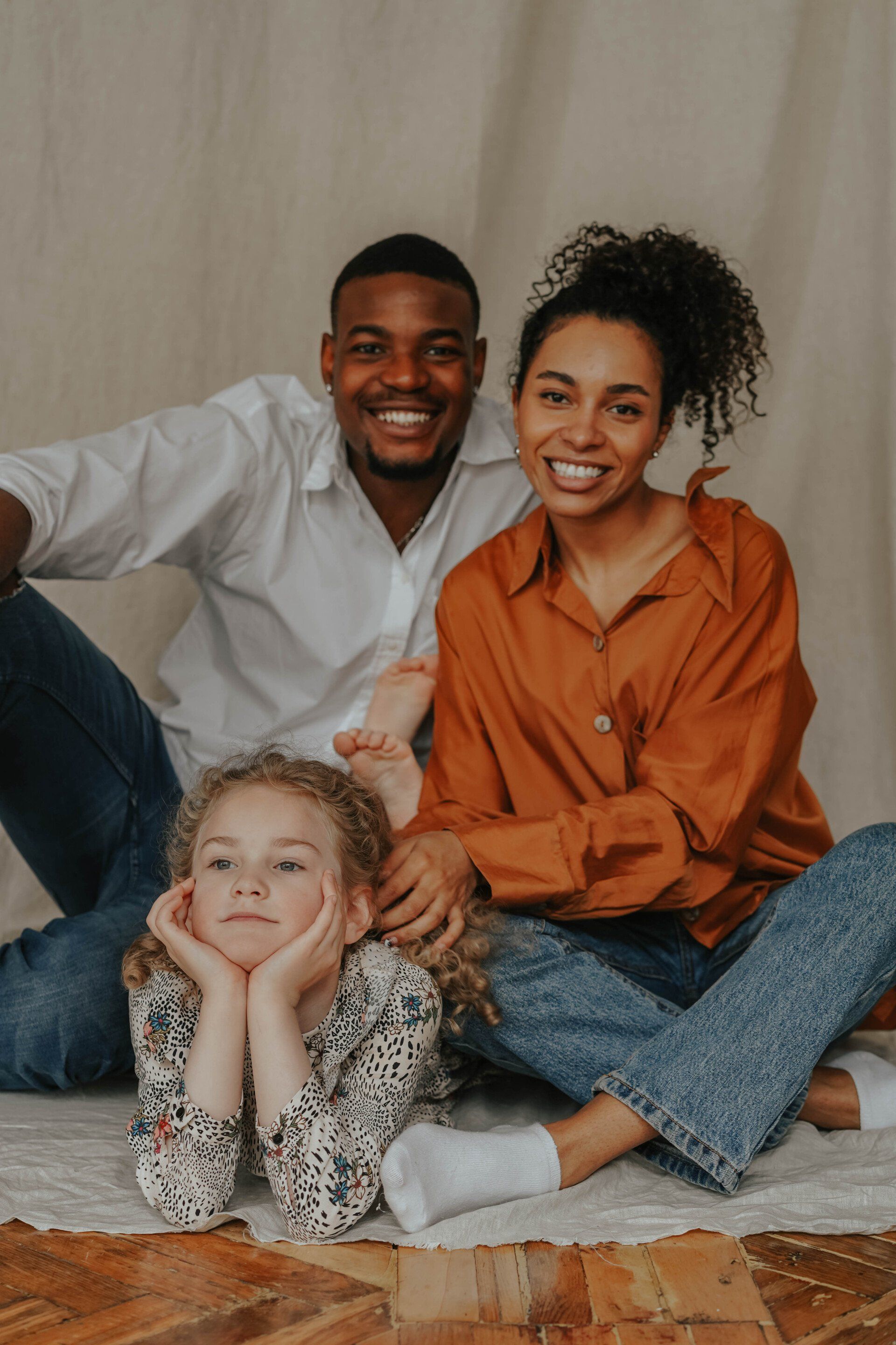 A family is sitting on the floor posing for a picture.