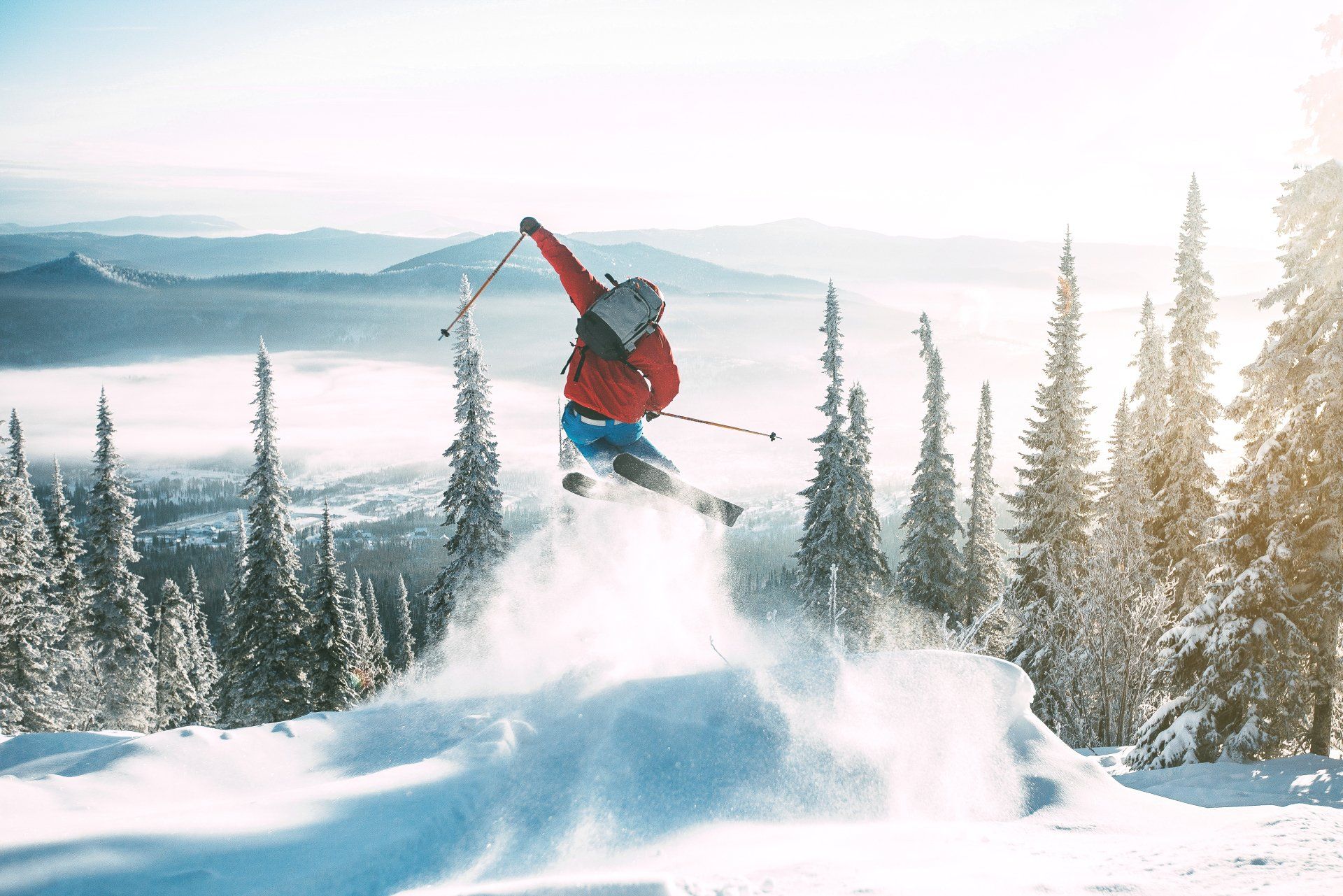 A person is jumping in the air while skiing down a snow covered slope.