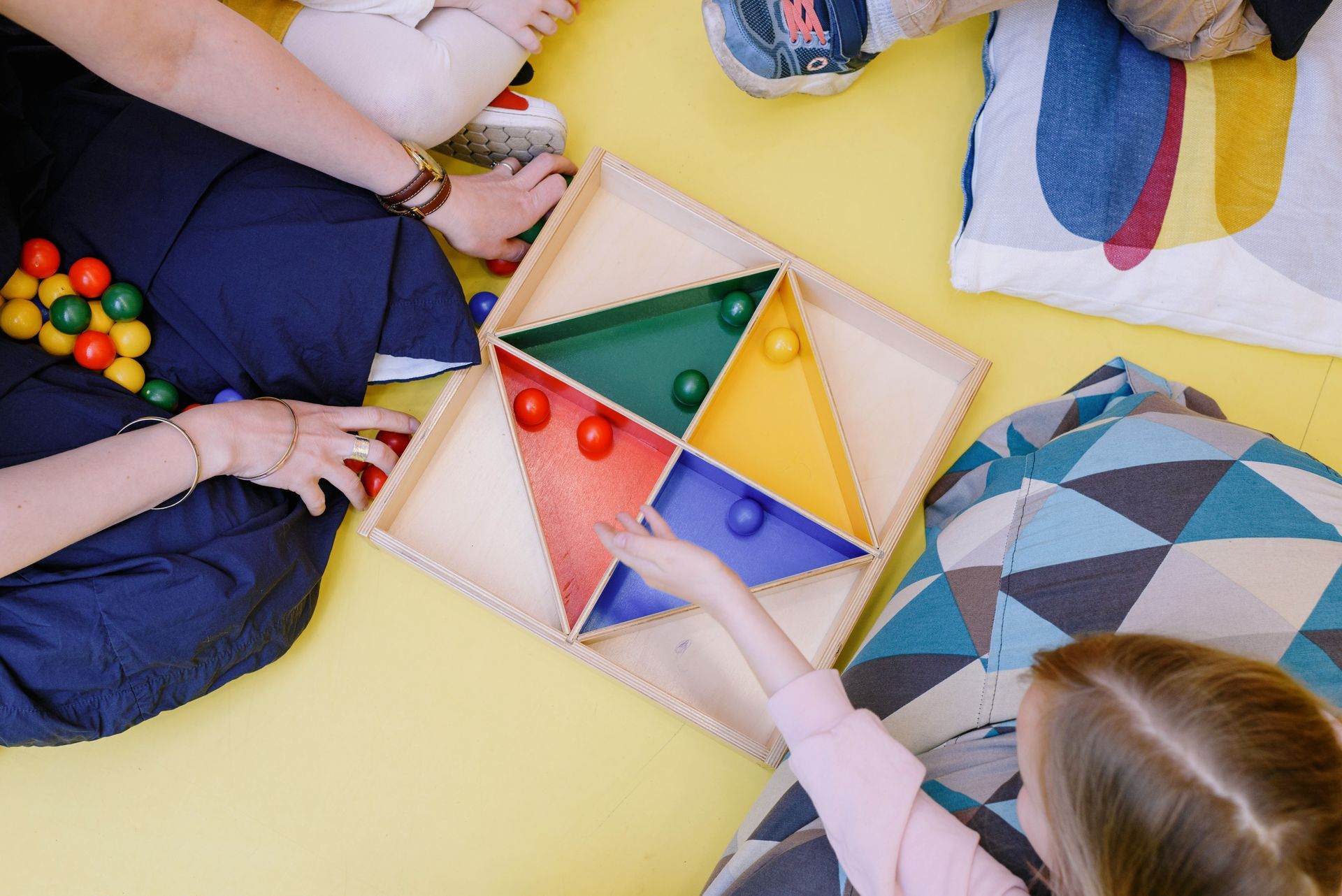 A group of children are playing with a wooden toy on the floor.