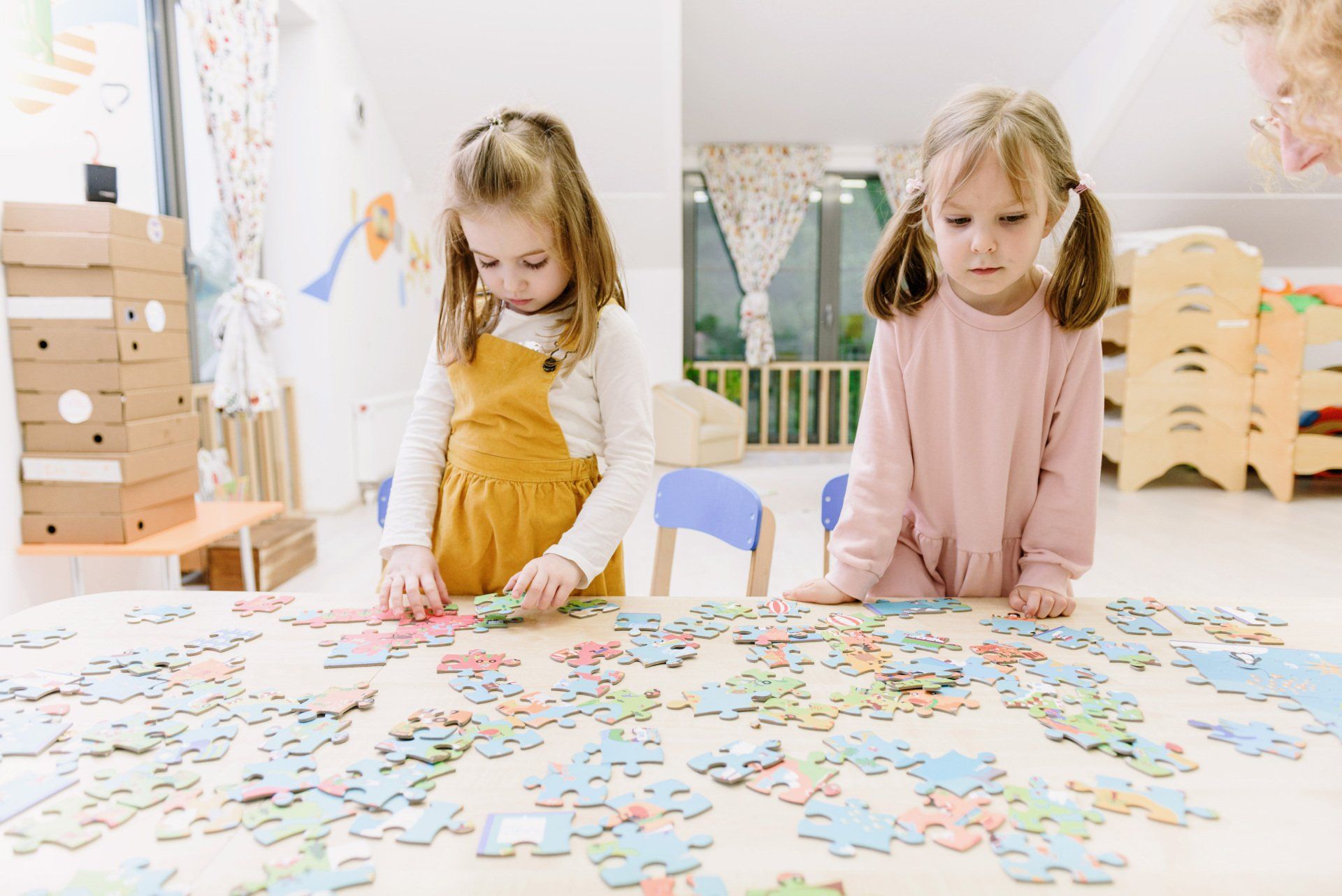 Deux petites filles sont assises à une table et jouent avec des puzzles.