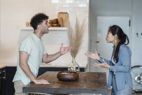 A man and a woman are sitting at a table having an argument.