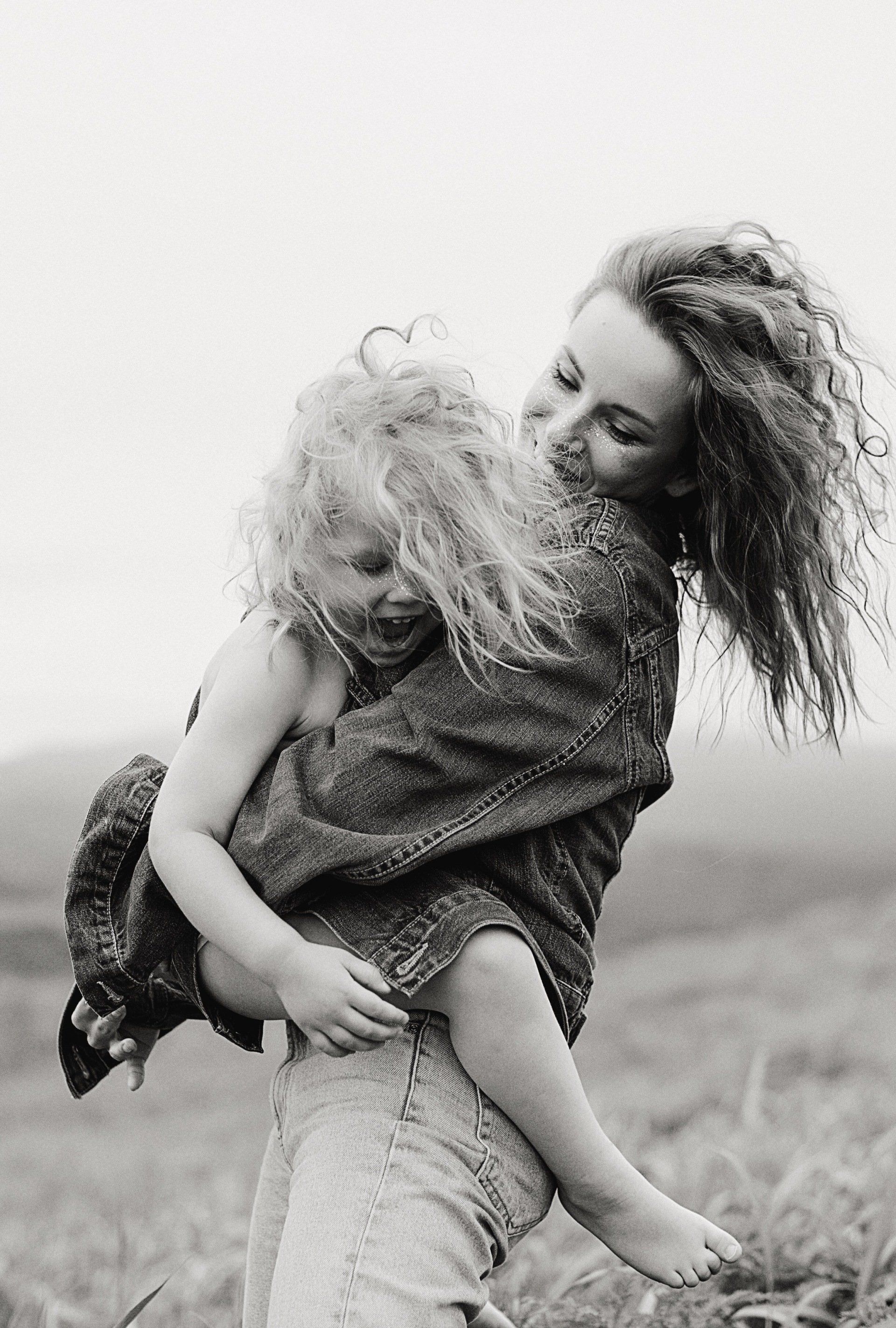 A woman is holding a little girl in her arms in a black and white photo.