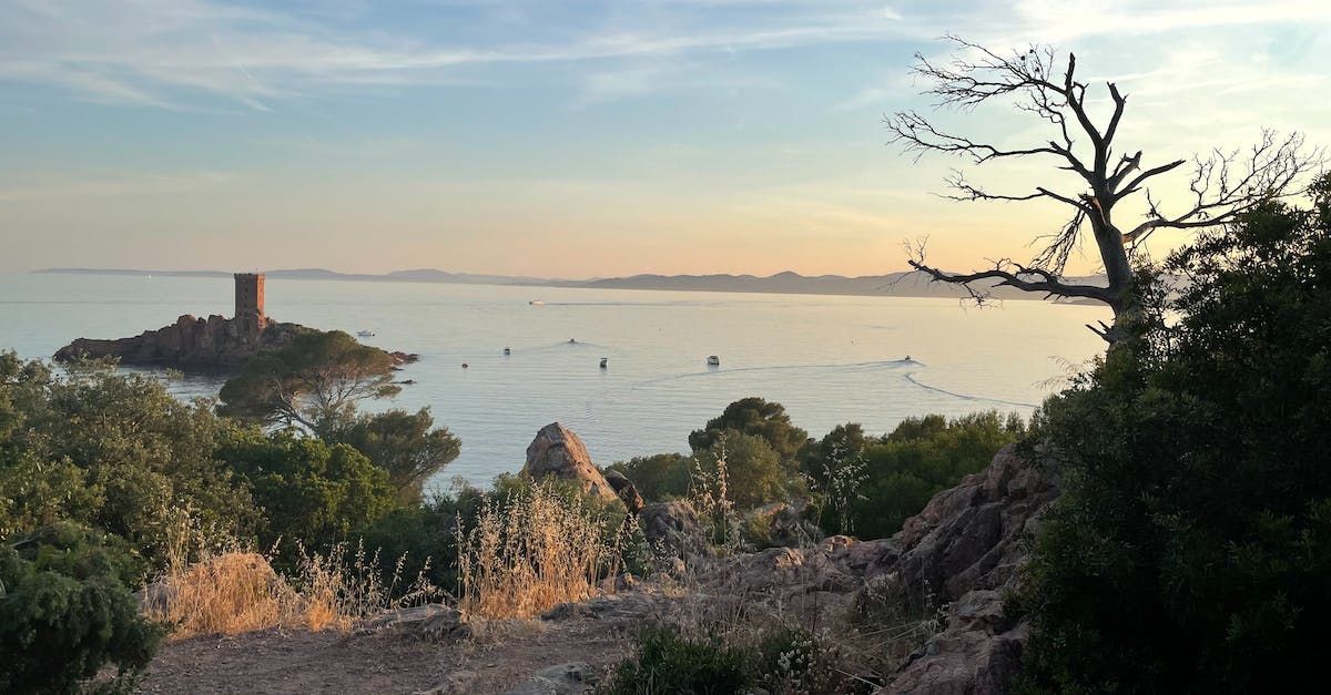 Paysage côtier avec une tour en pierre sur un îlot, l'eau et le rivage au coucher du soleil.