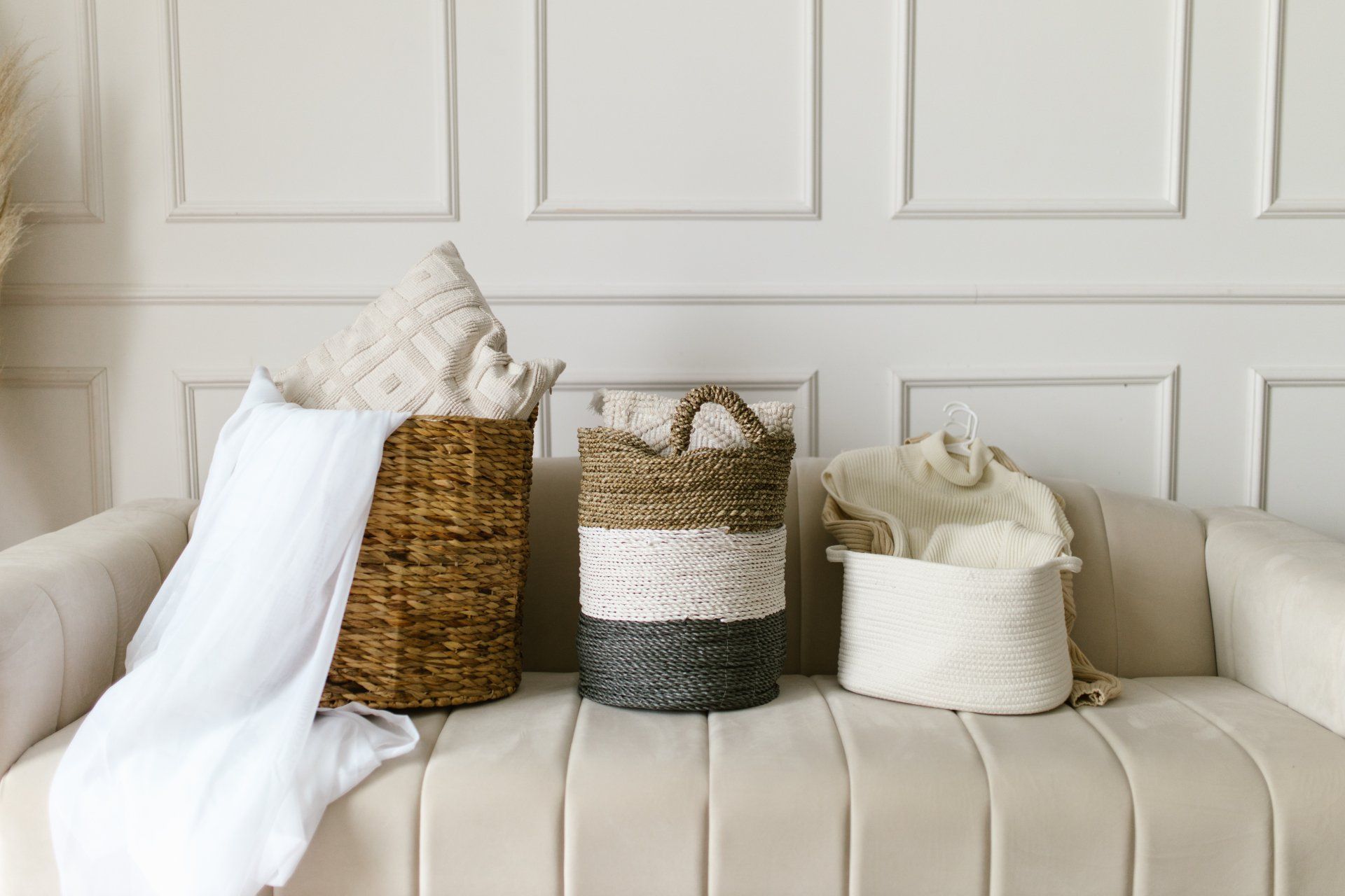 Three baskets are sitting on a couch in a living room.
