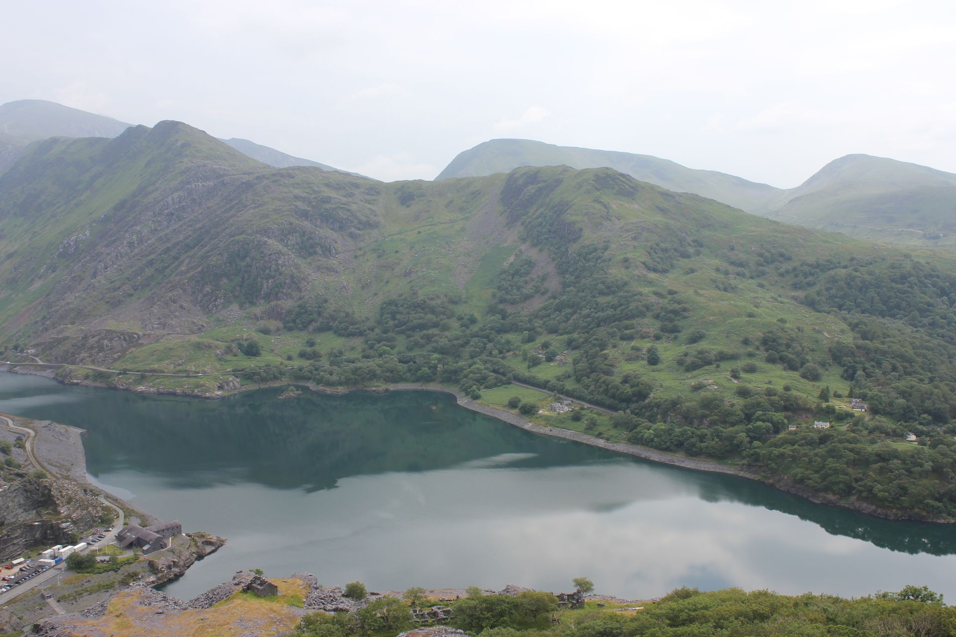 a large body of water surrounded by mountains and trees .