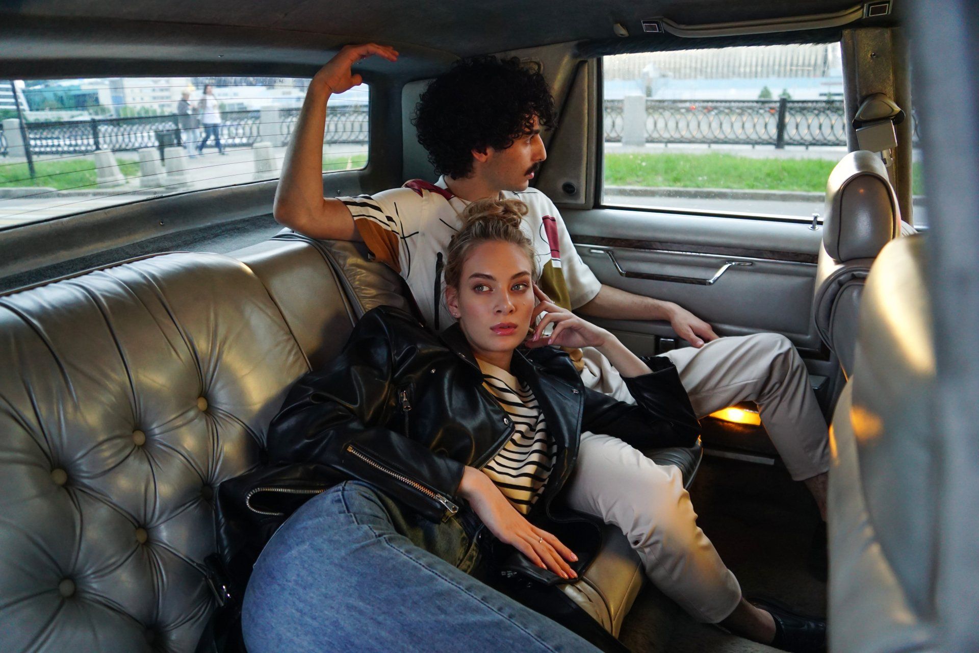 A man and a woman are sitting in the back seat of a limousine.