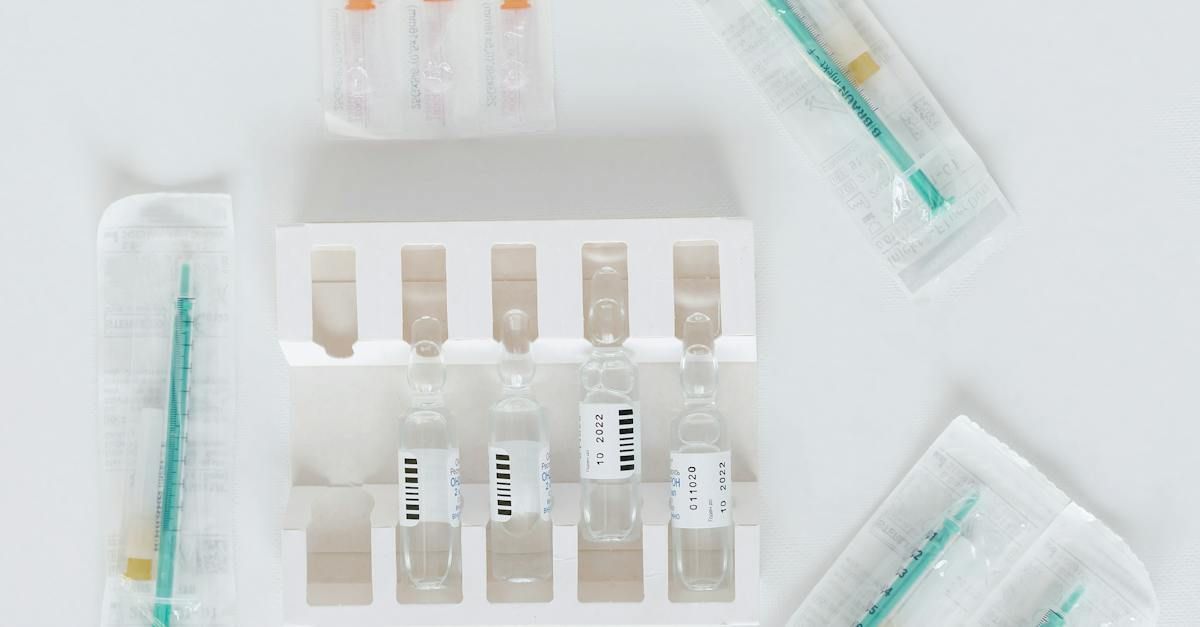 Syringes and small vials arranged on a white medical tray and surface