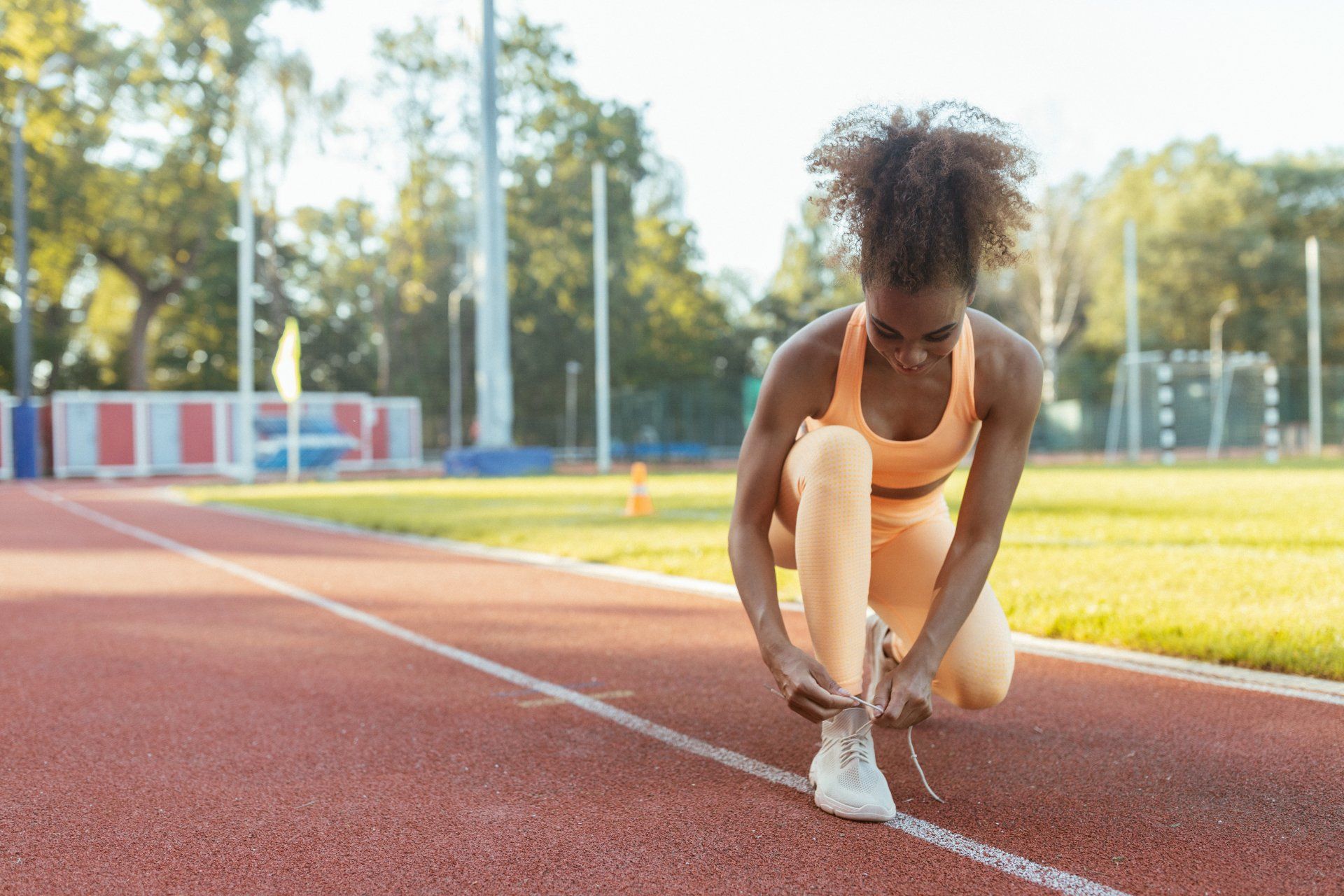 A woman is tying her shoes on a track.
