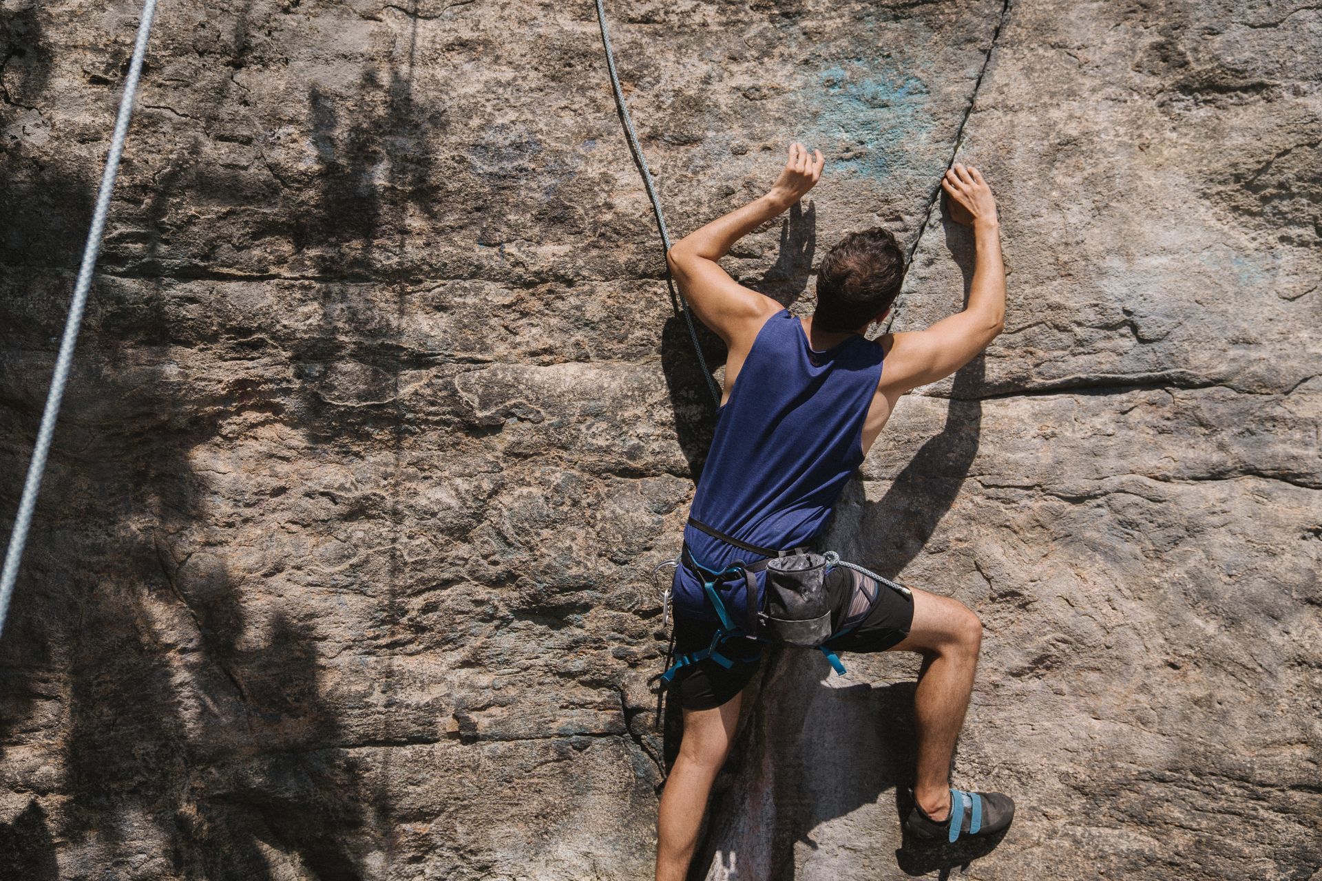 A man is climbing a rock wall with a rope.