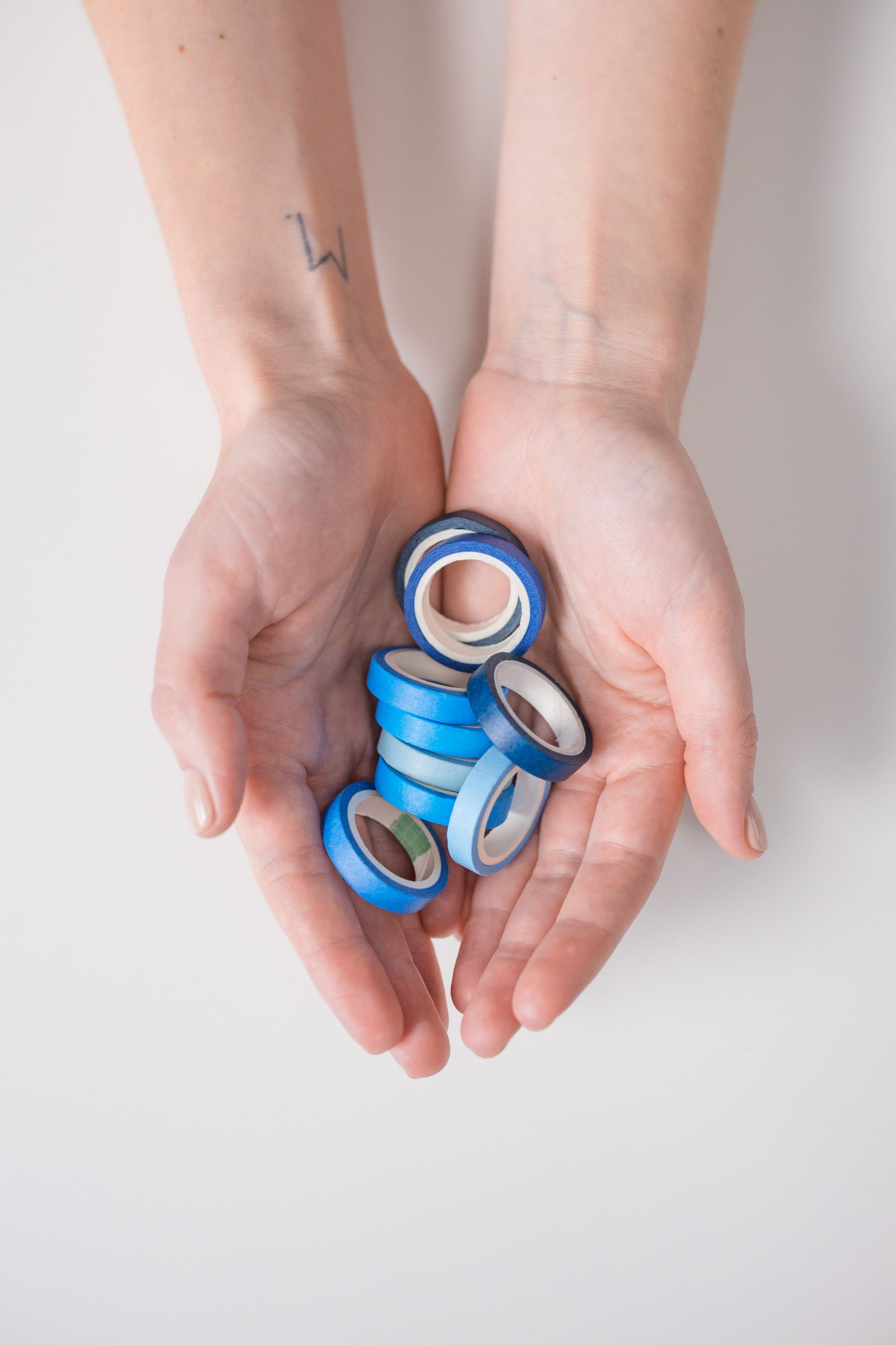 A person is holding a pile of blue tape in their hands.