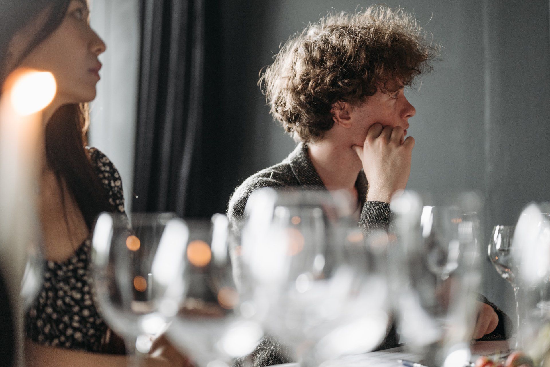 A man and a woman are sitting at a table with wine glasses.