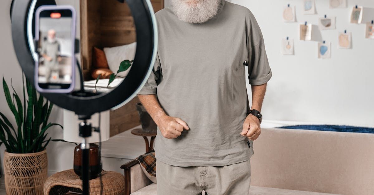A man with a beard is standing in front of a ring light in a living room.