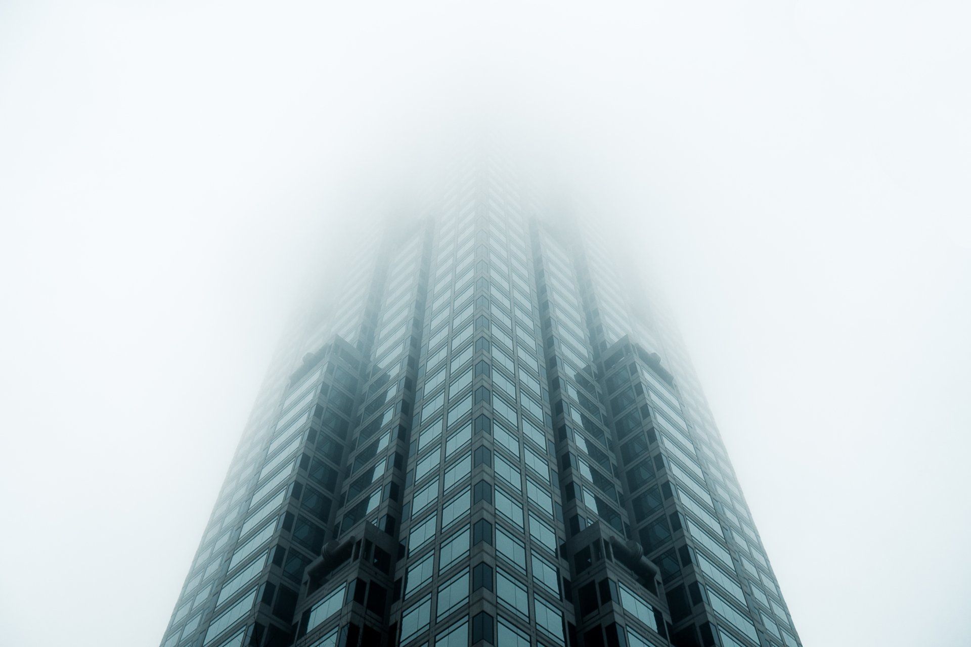 Looking up at a tall building in the fog.