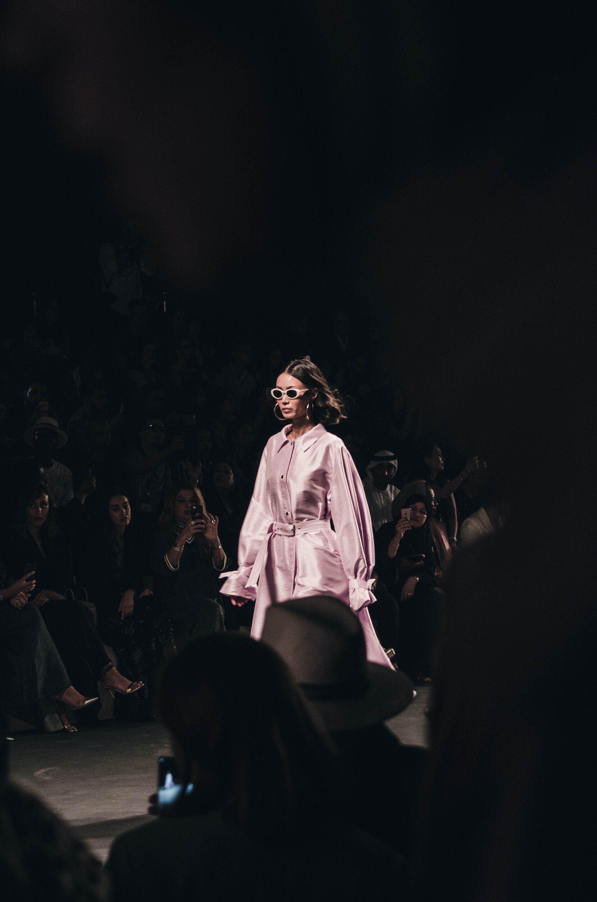 A woman is walking down a runway at a fashion show.