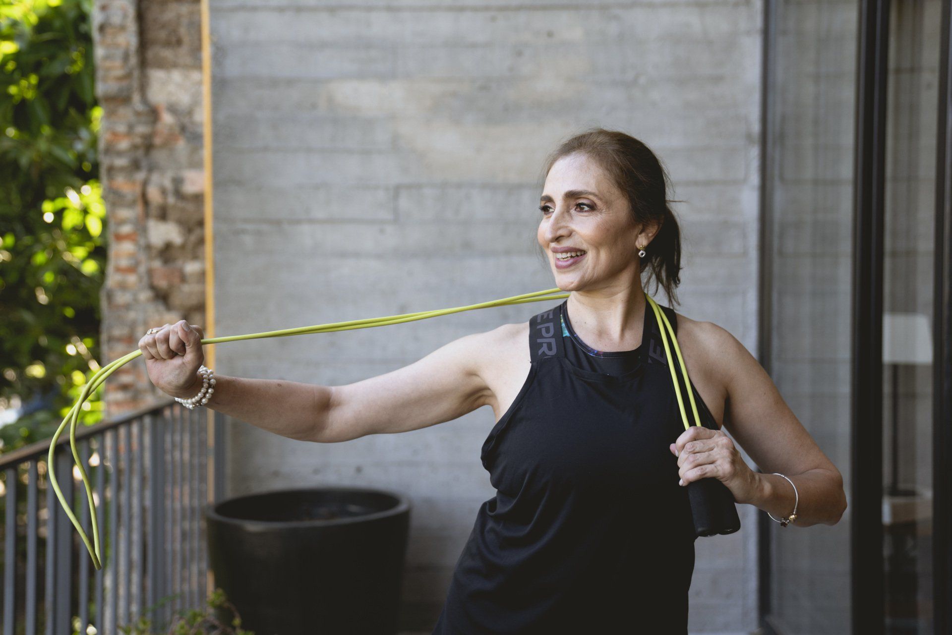 Woman stretching with resistance band outdoors beside a stone wall