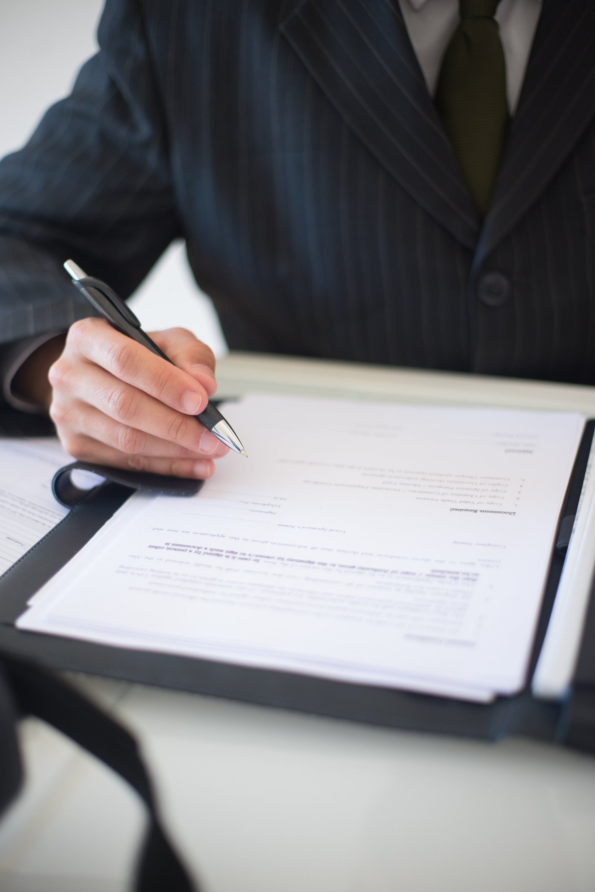 A man in a suit and tie is writing on a piece of paper