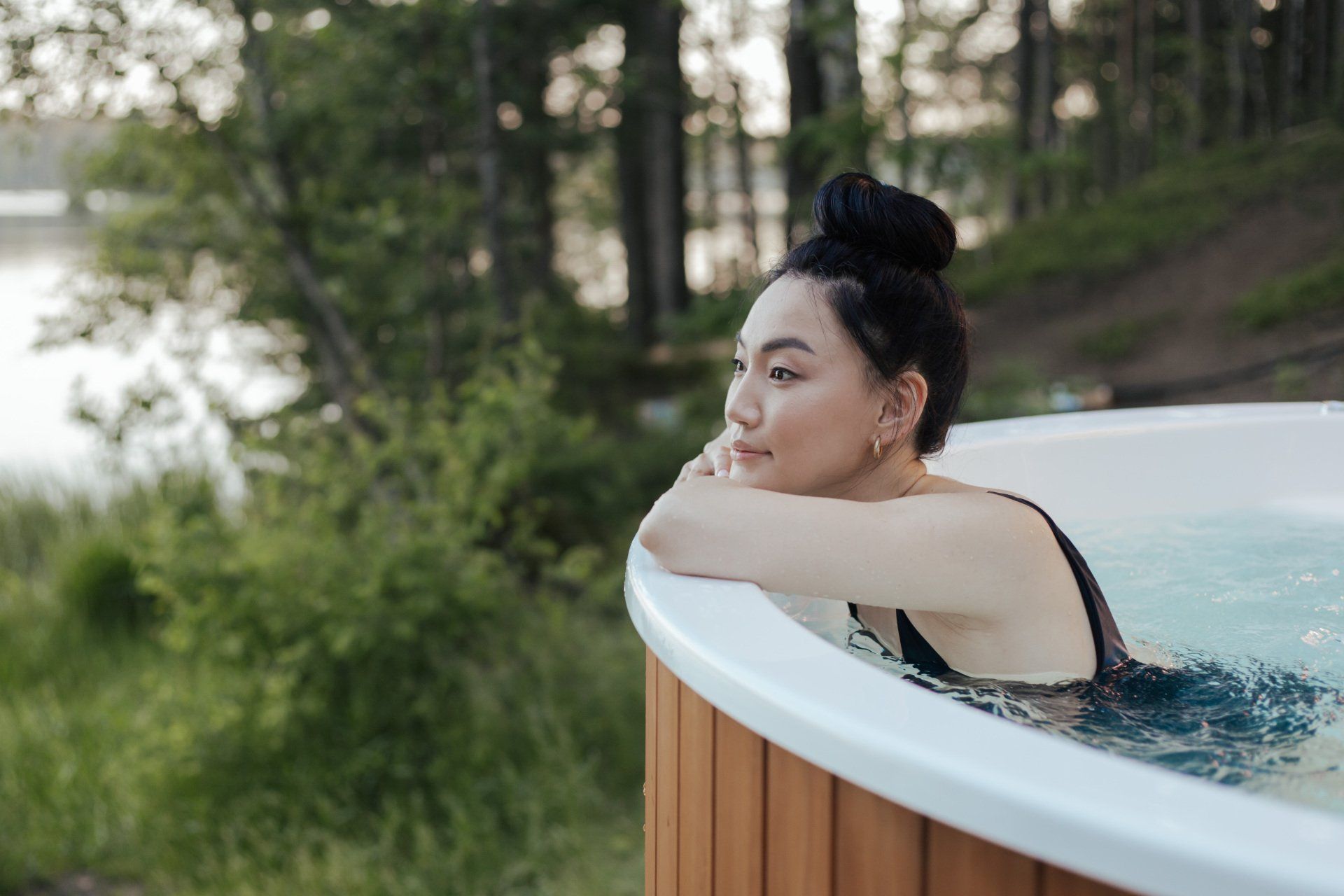 Une femme est assise dans un bain à remous et regarde l'eau.