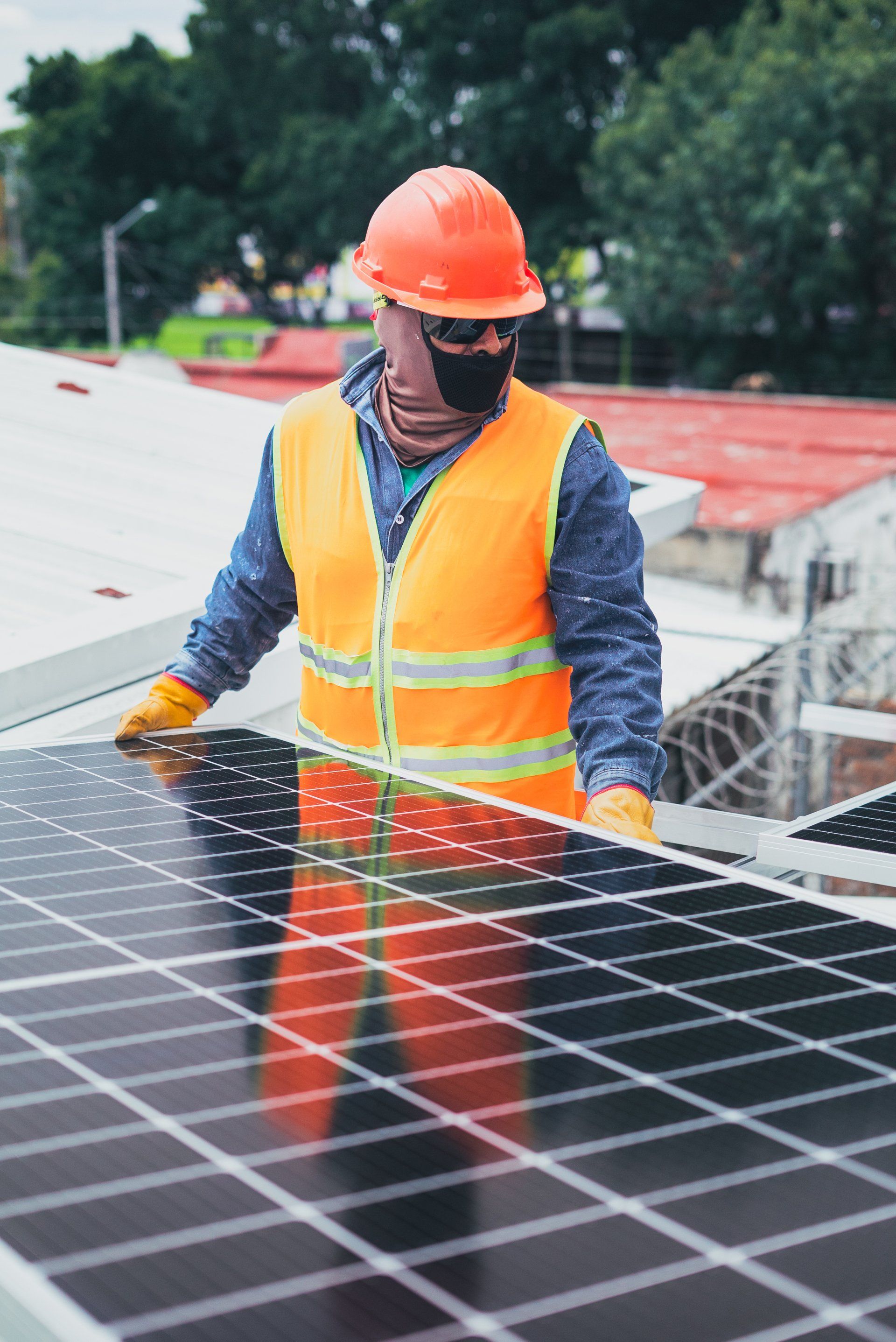 Un hombre que lleva casco y chaleco de seguridad está trabajando en un panel solar.