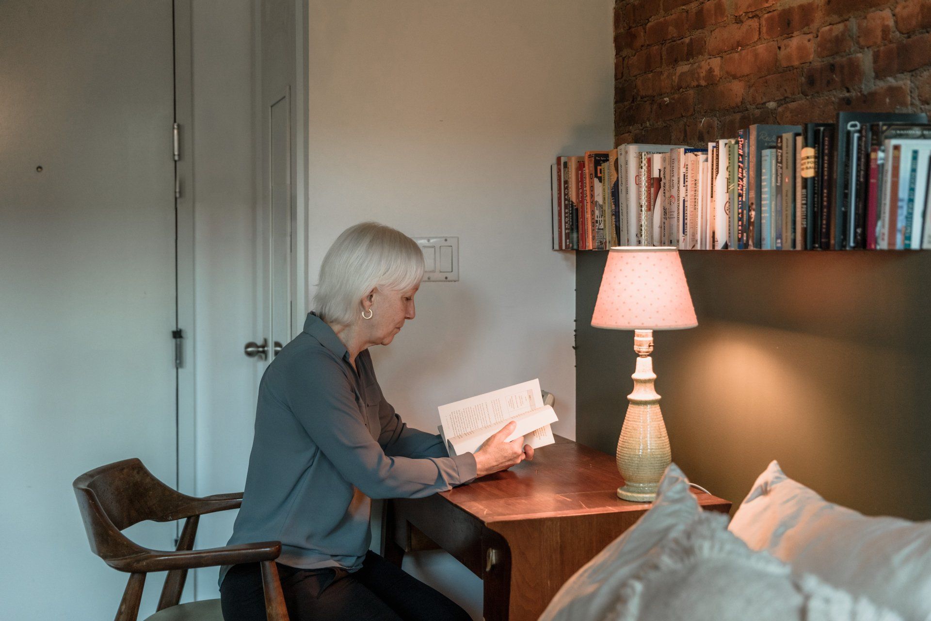 A woman is sitting at a desk reading a book.