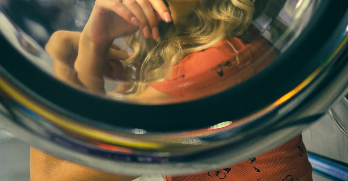 una donna sta guardando il suo riflesso nello specchio di una lavatrice