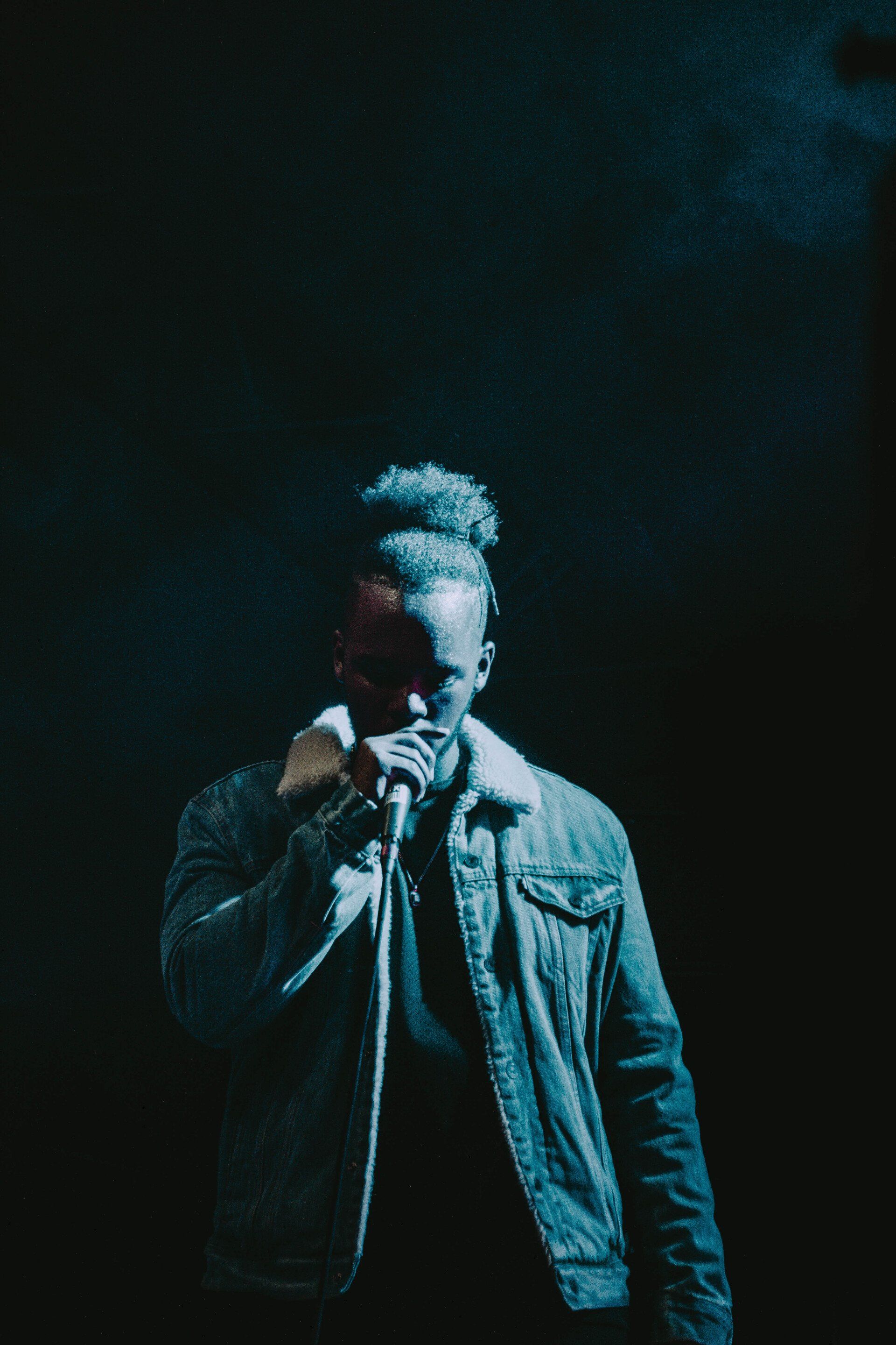 A man is singing into a microphone in a dark room.