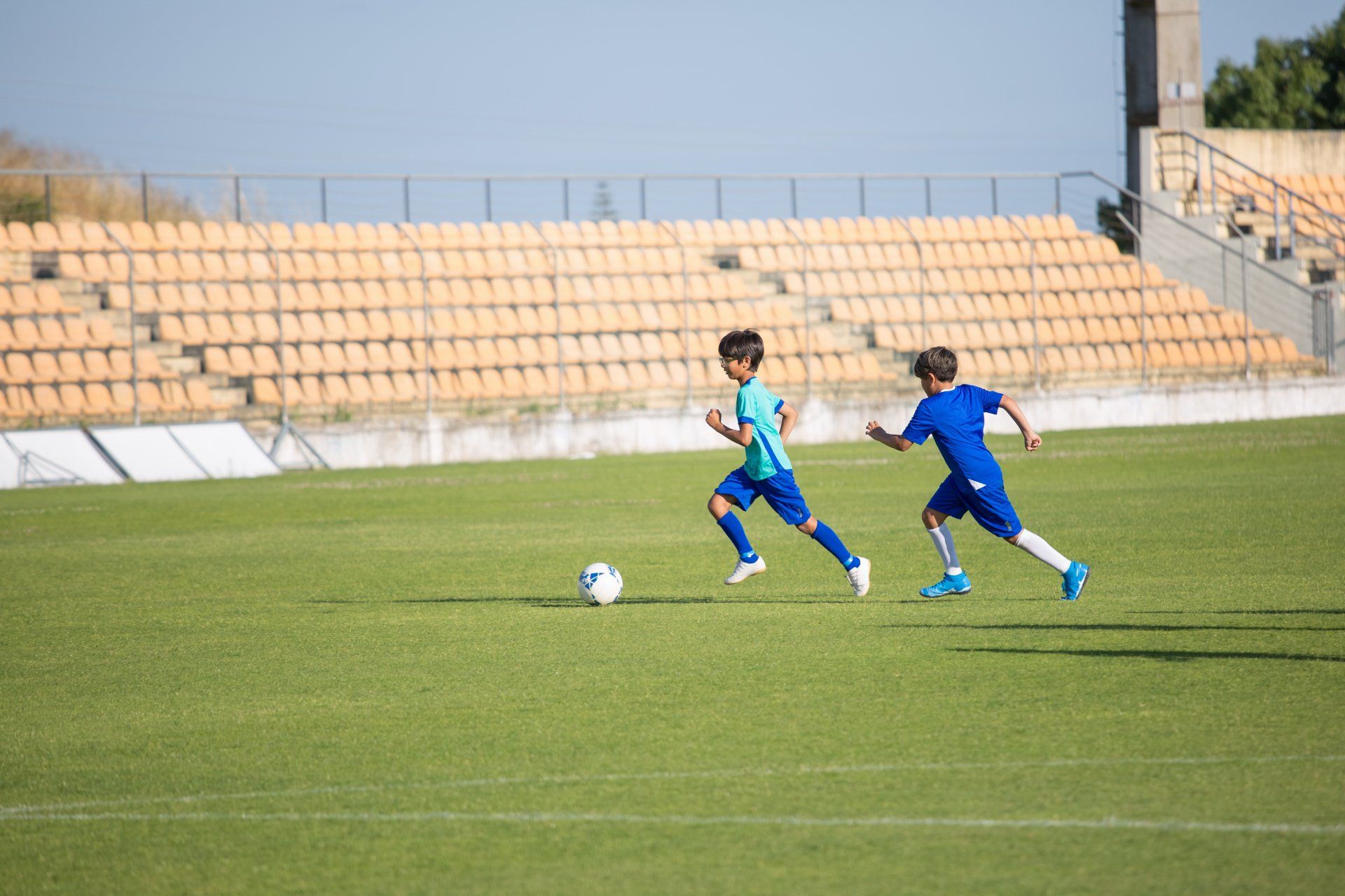 Two young boys are playing soccer on a soccer field.