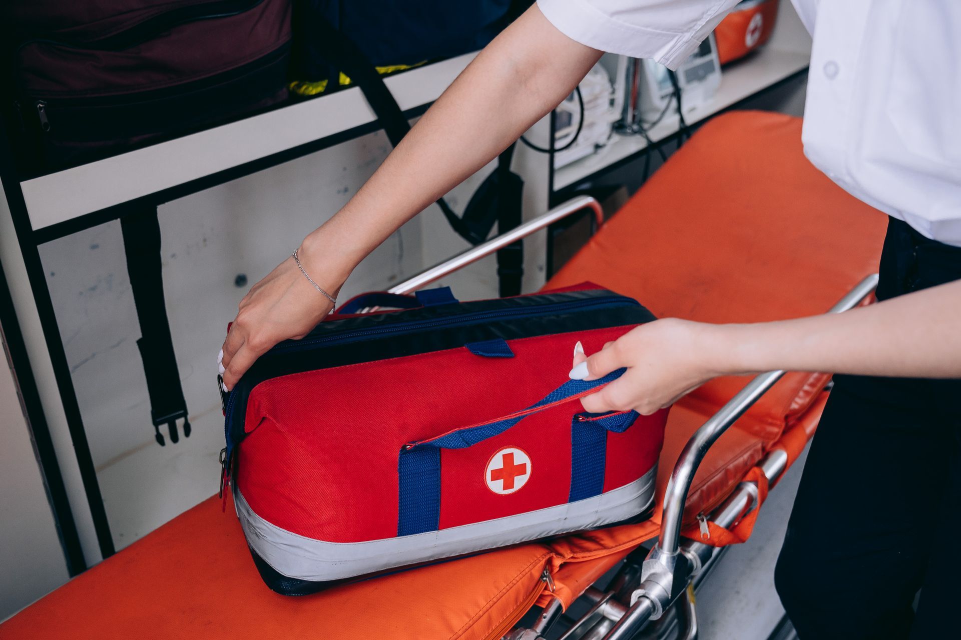 A woman is putting a first aid kit on an ambulance.