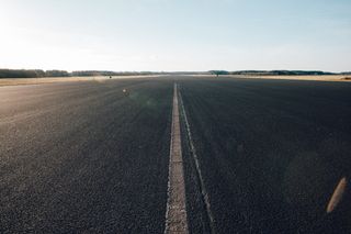 Empty asphalt road stretching into a flat horizon under a pale sky.