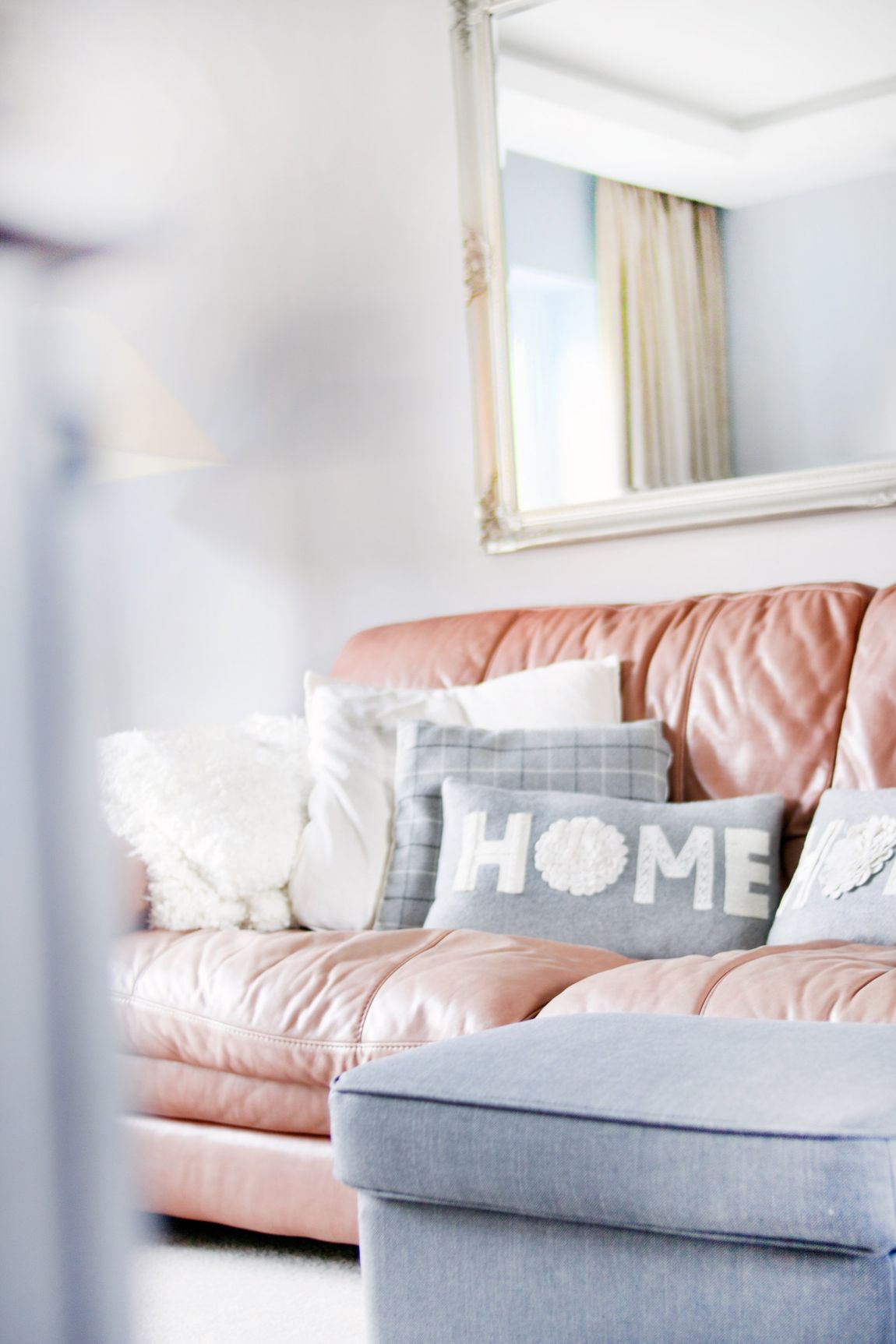 A living room with a pink leather couch and a gray ottoman.
