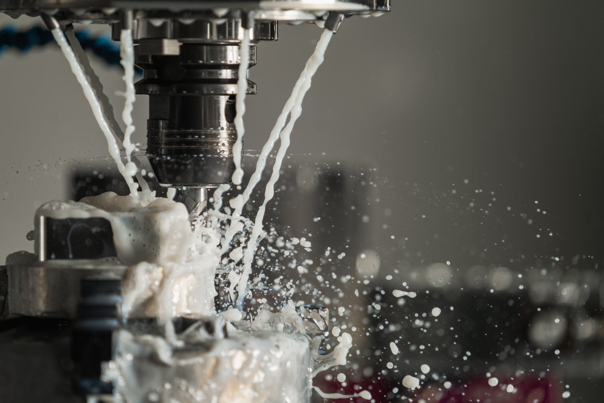 A machine is cutting a piece of metal with liquid coming out of it.
