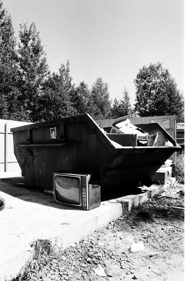Picture of a dumpster with trash in and around it.