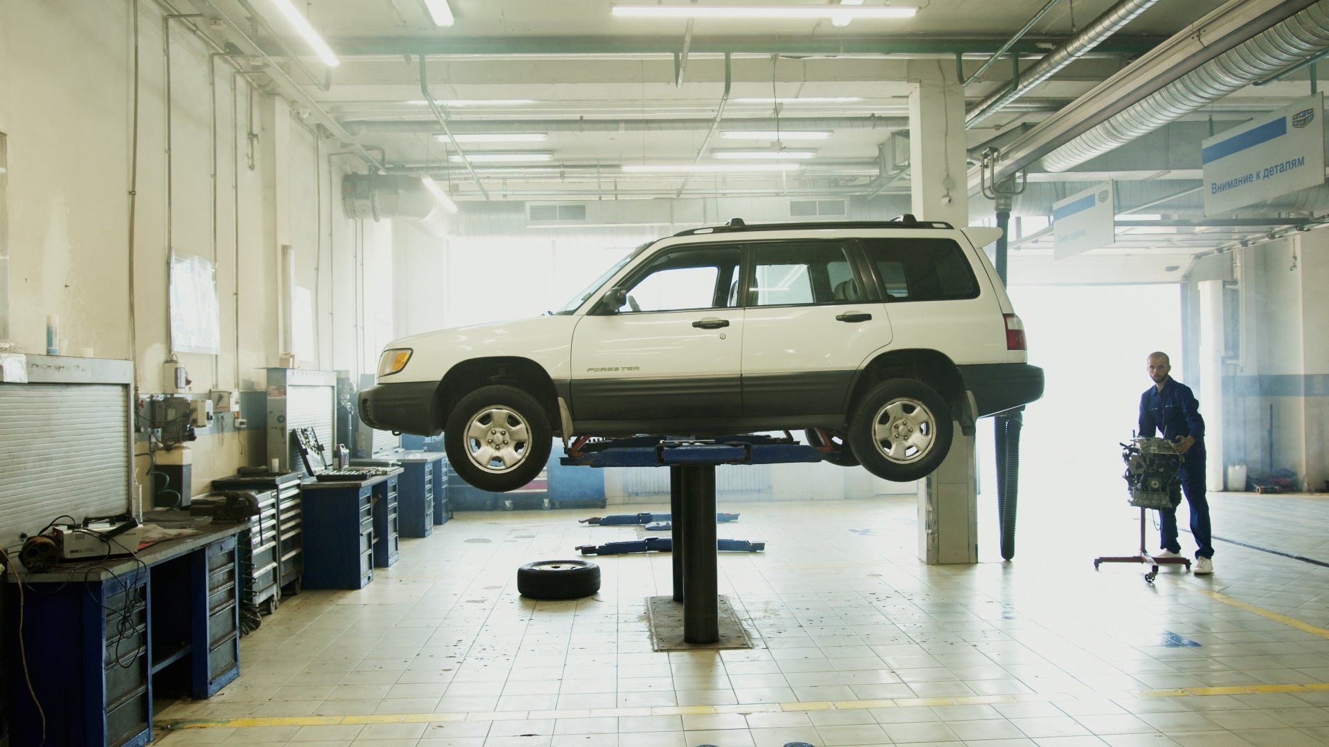 A white suv is sitting on top of a lift in a garage.