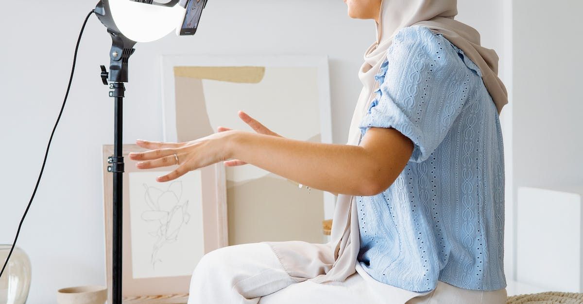 A woman wearing a hijab is sitting in front of a microphone.