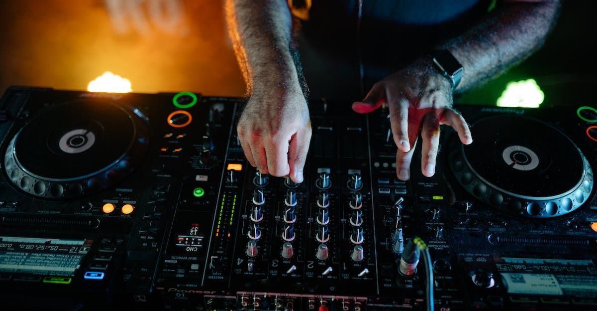 A dj is playing music on a mixer in a dark room.