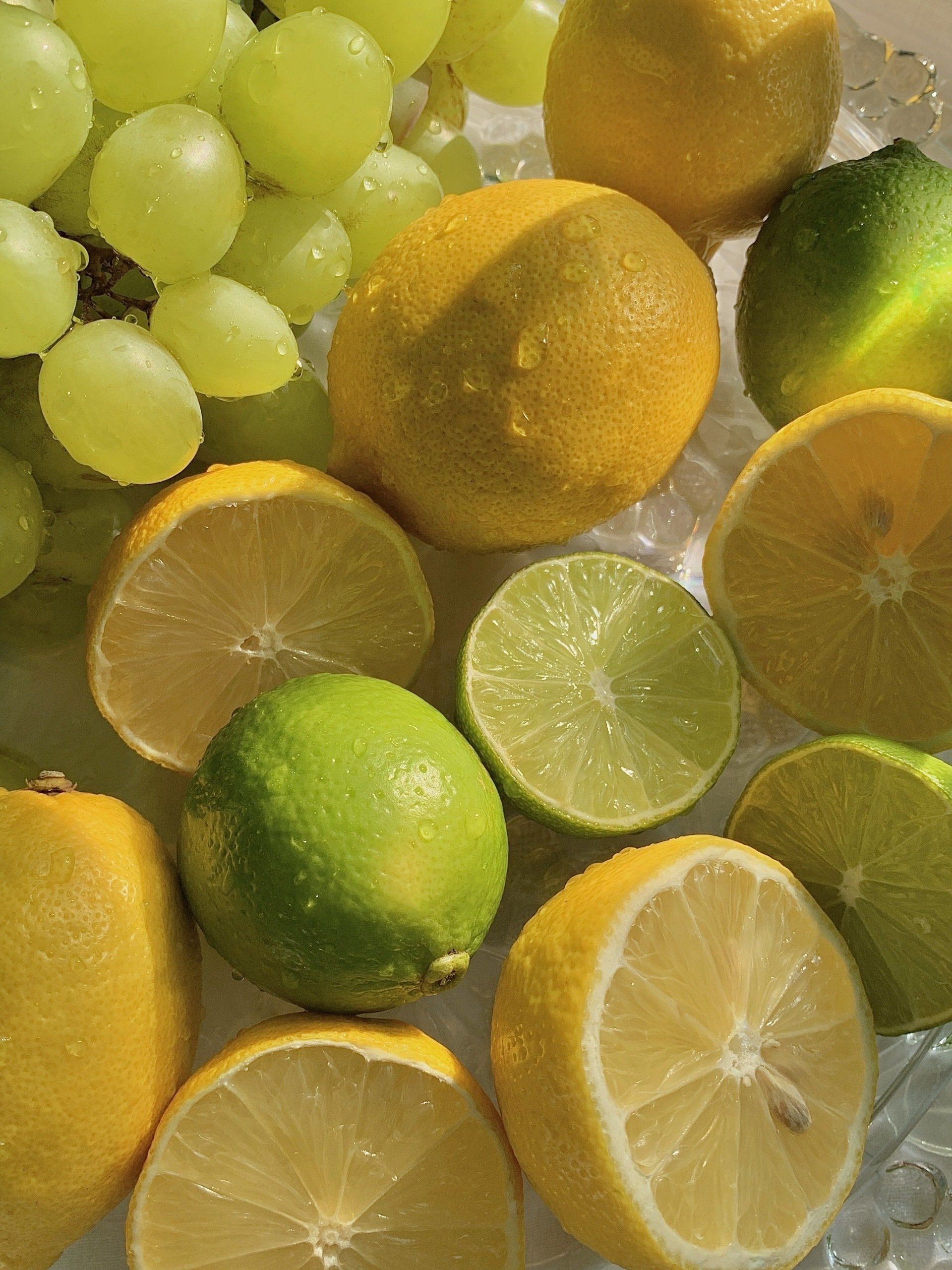 A glass bowl filled with lemons limes and grapes
