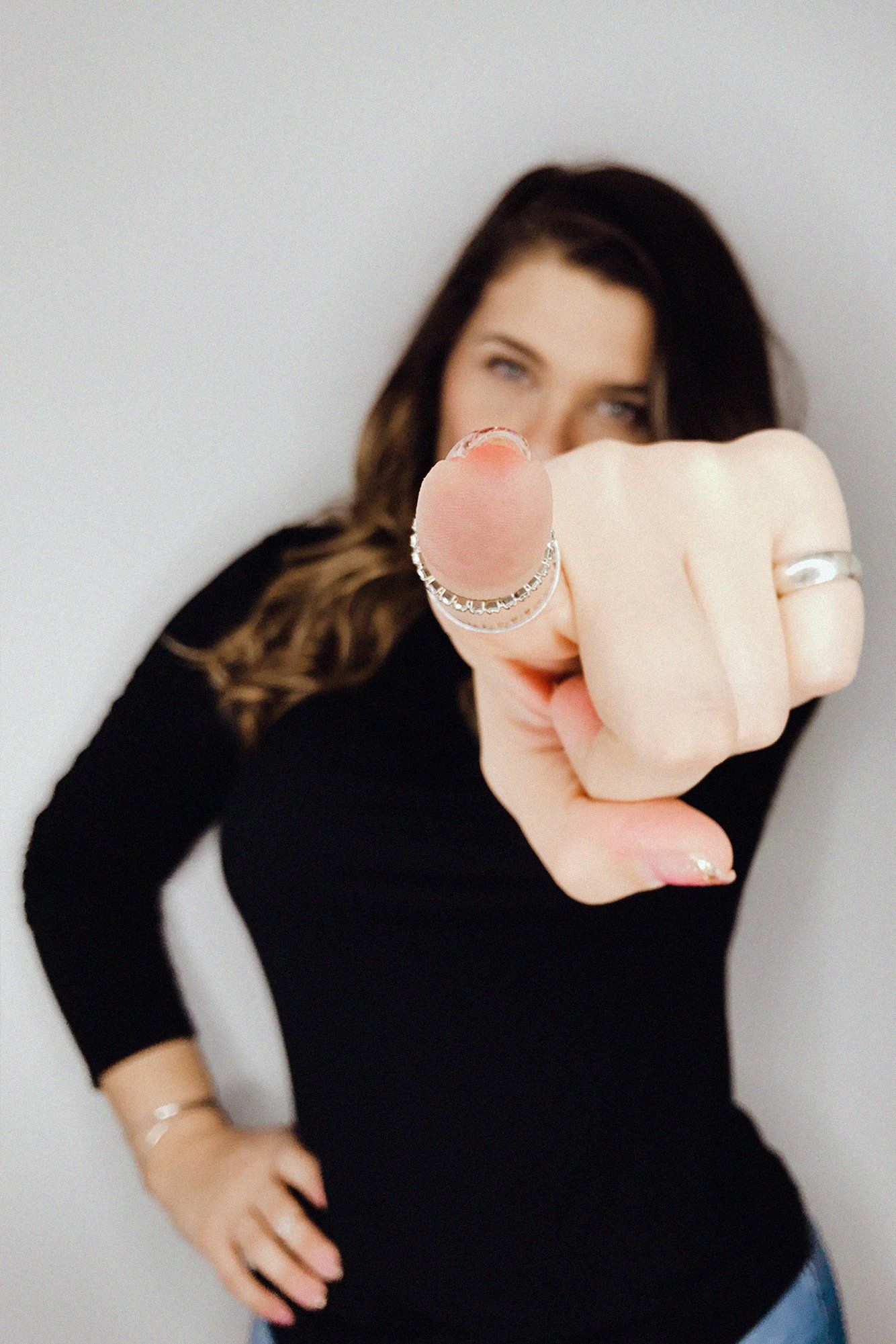 A woman with a ring on her finger pointing at the camera