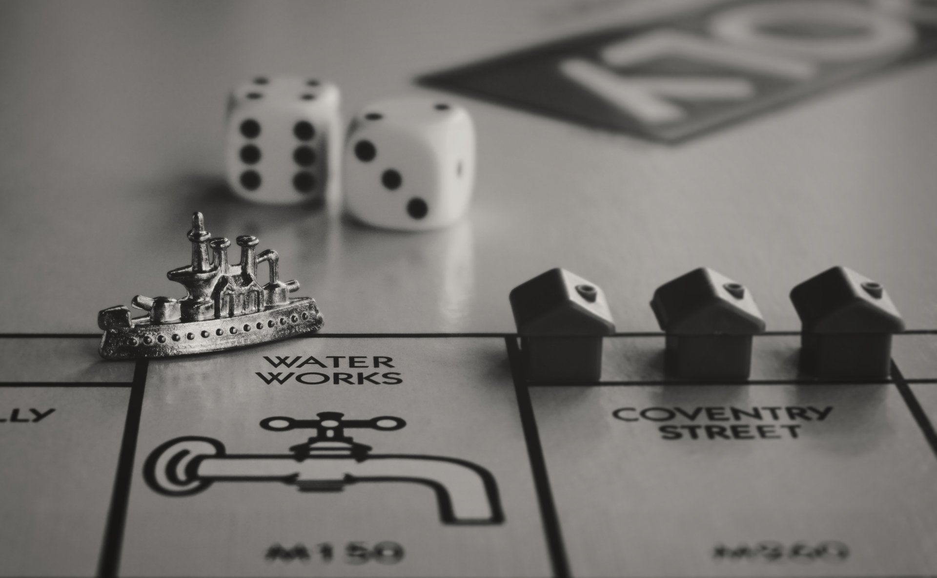 Uma foto em preto e branco de um jogo de tabuleiro de monopólio com dados e casas.