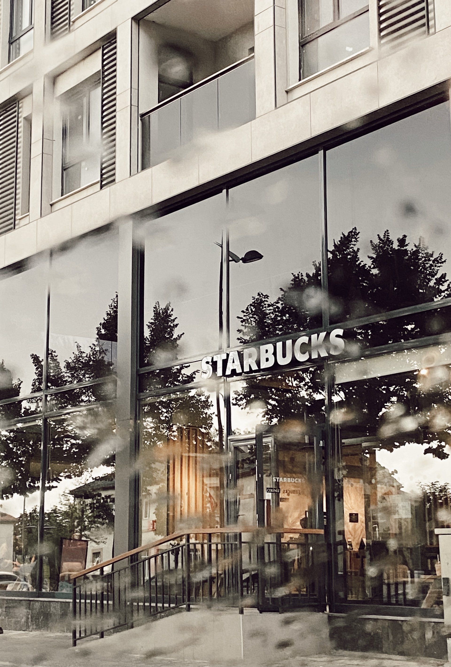 Starbucks storefront with glass windows and outdoor seating on a city street