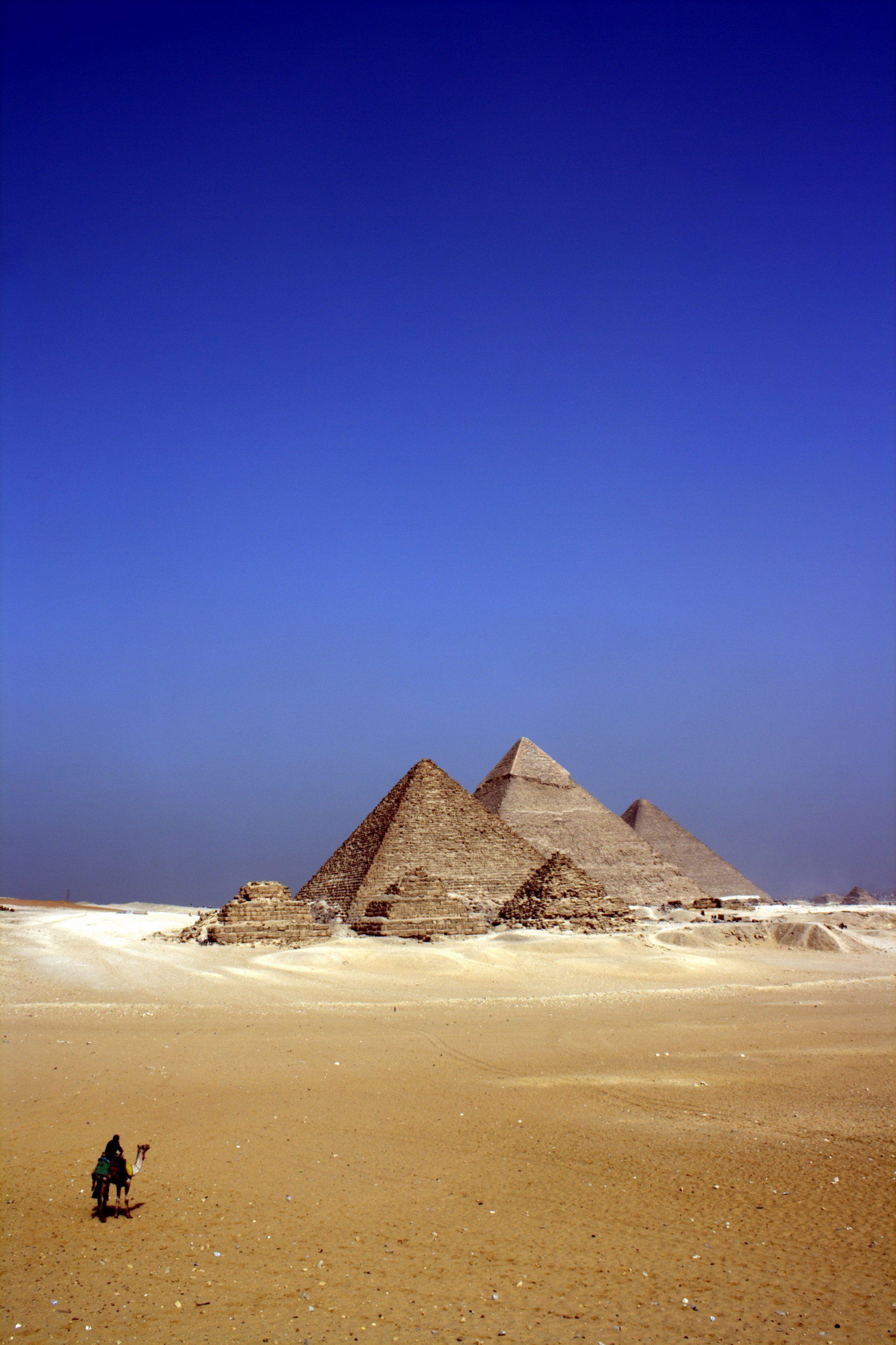Three pyramids in the desert with a blue sky in the background